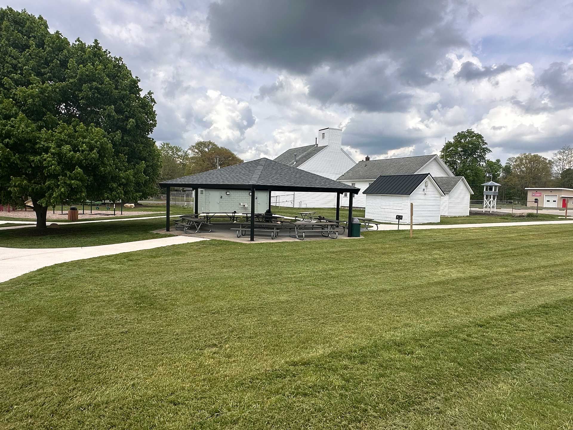 a picnic shelter in the middle of a grassy field