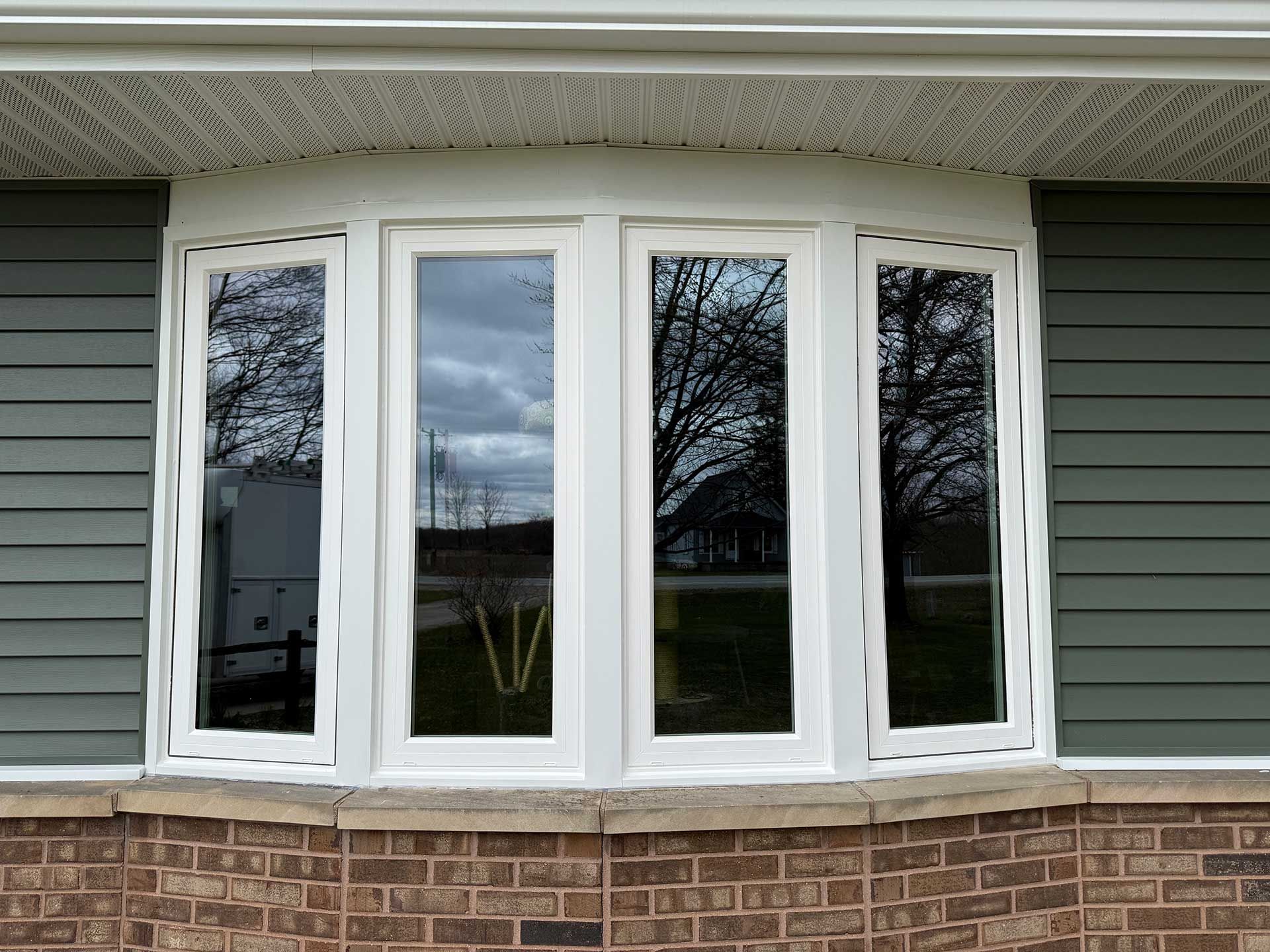a white bay window on the side of a brick house