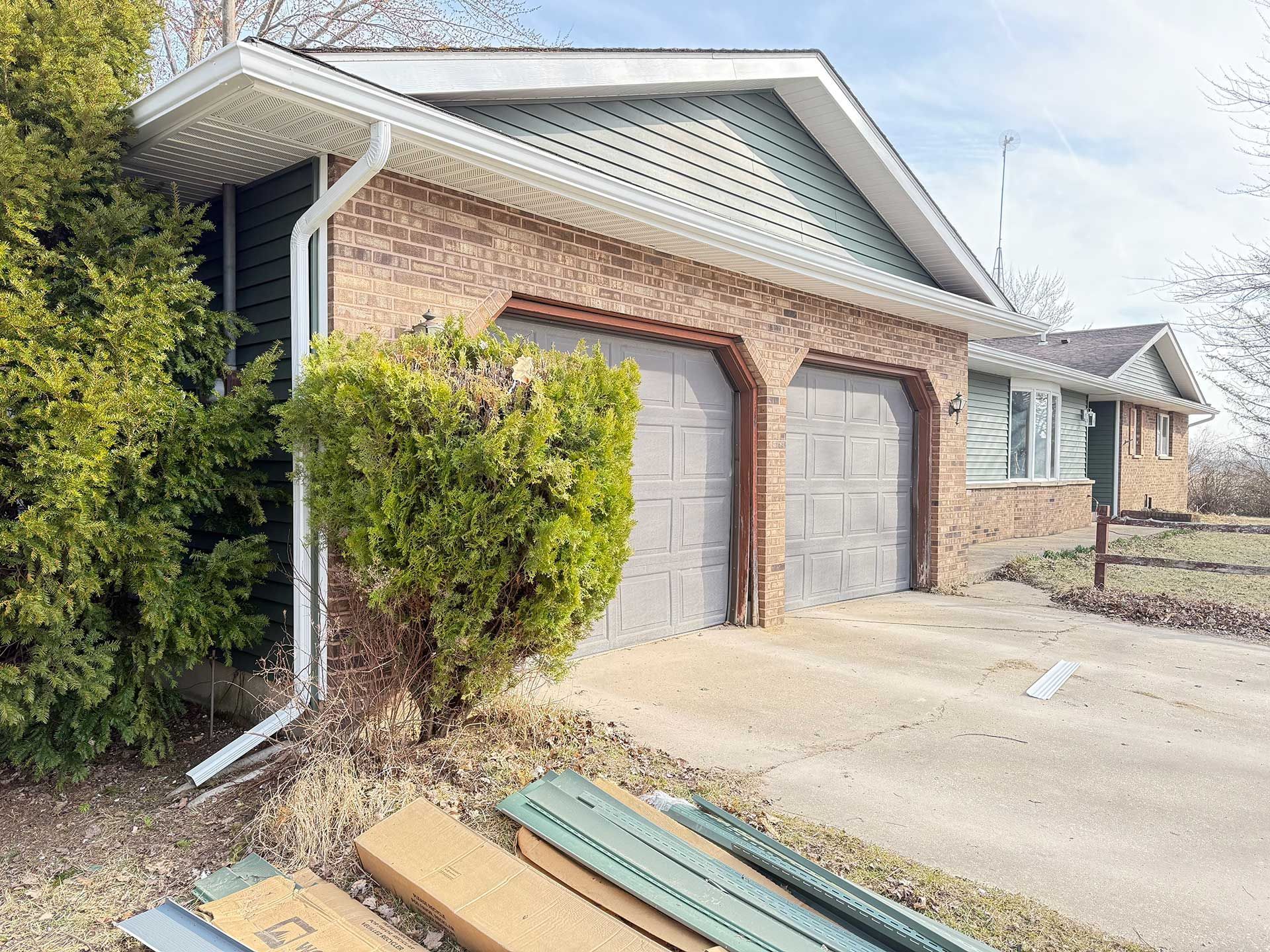 a brick house with two garage doors and a gutter on the side of it