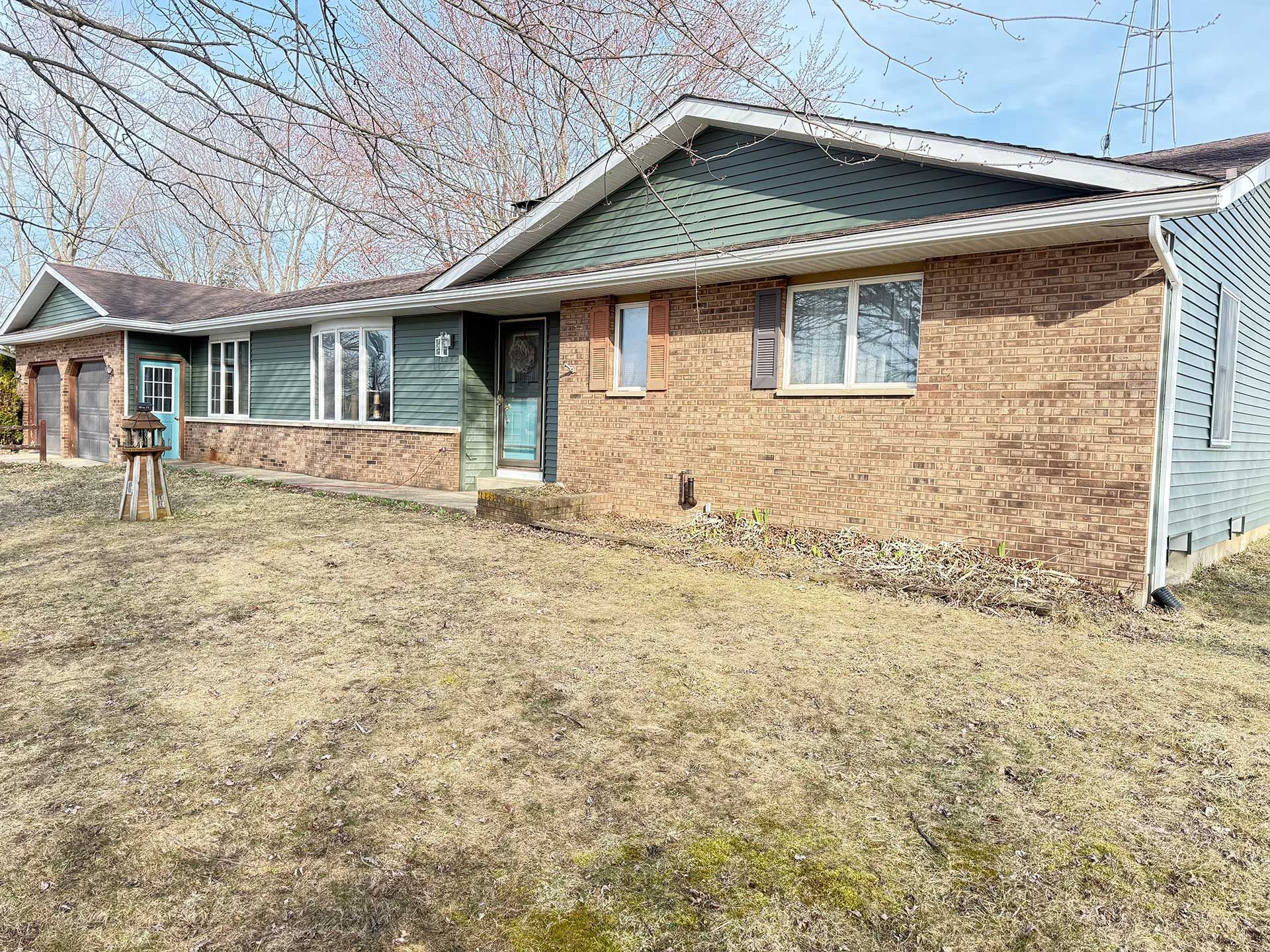 a brick house with a brown roof is sitting on top of a lush green field