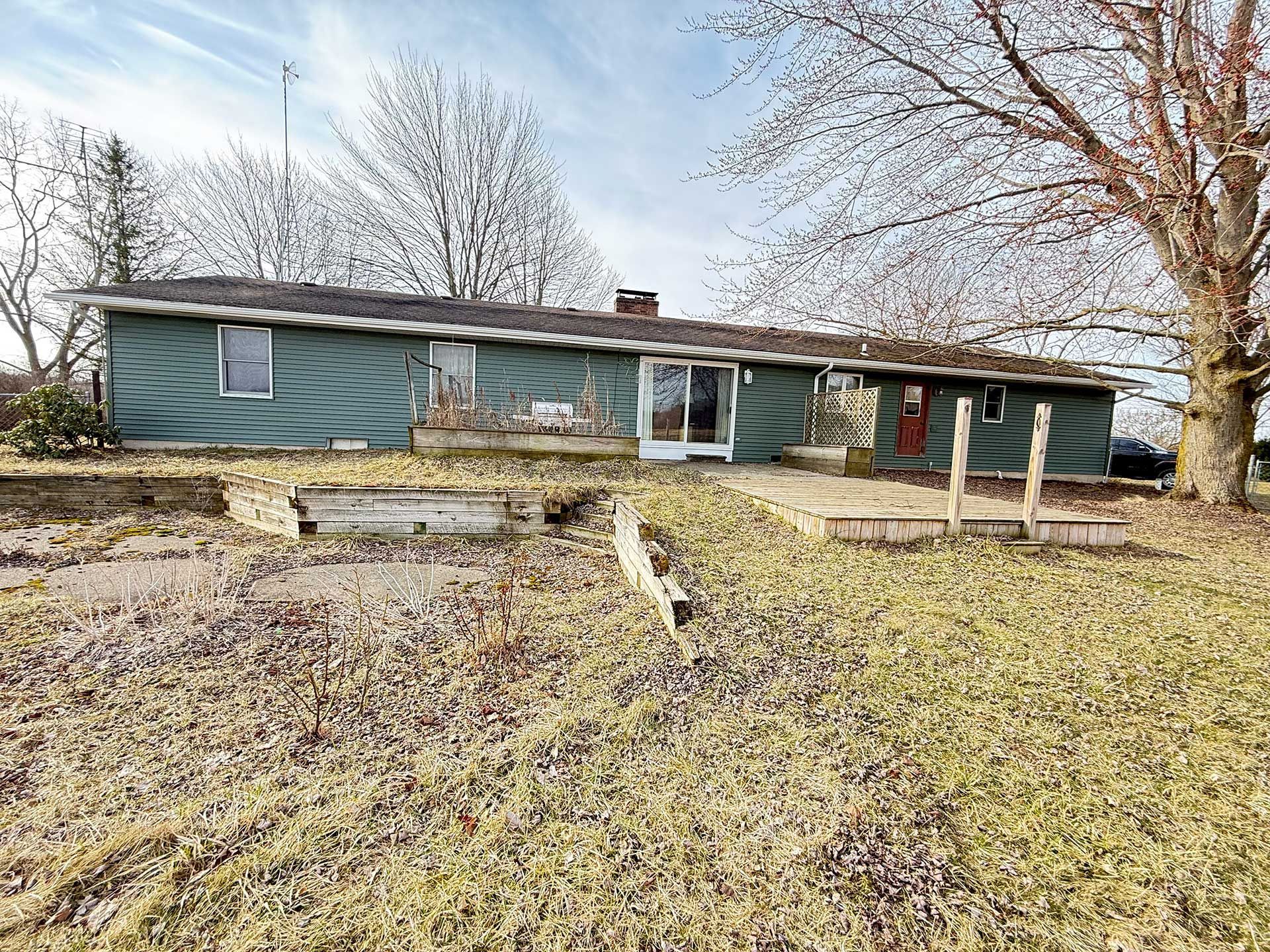 a bungalow house is sitting in the middle of a grassy field