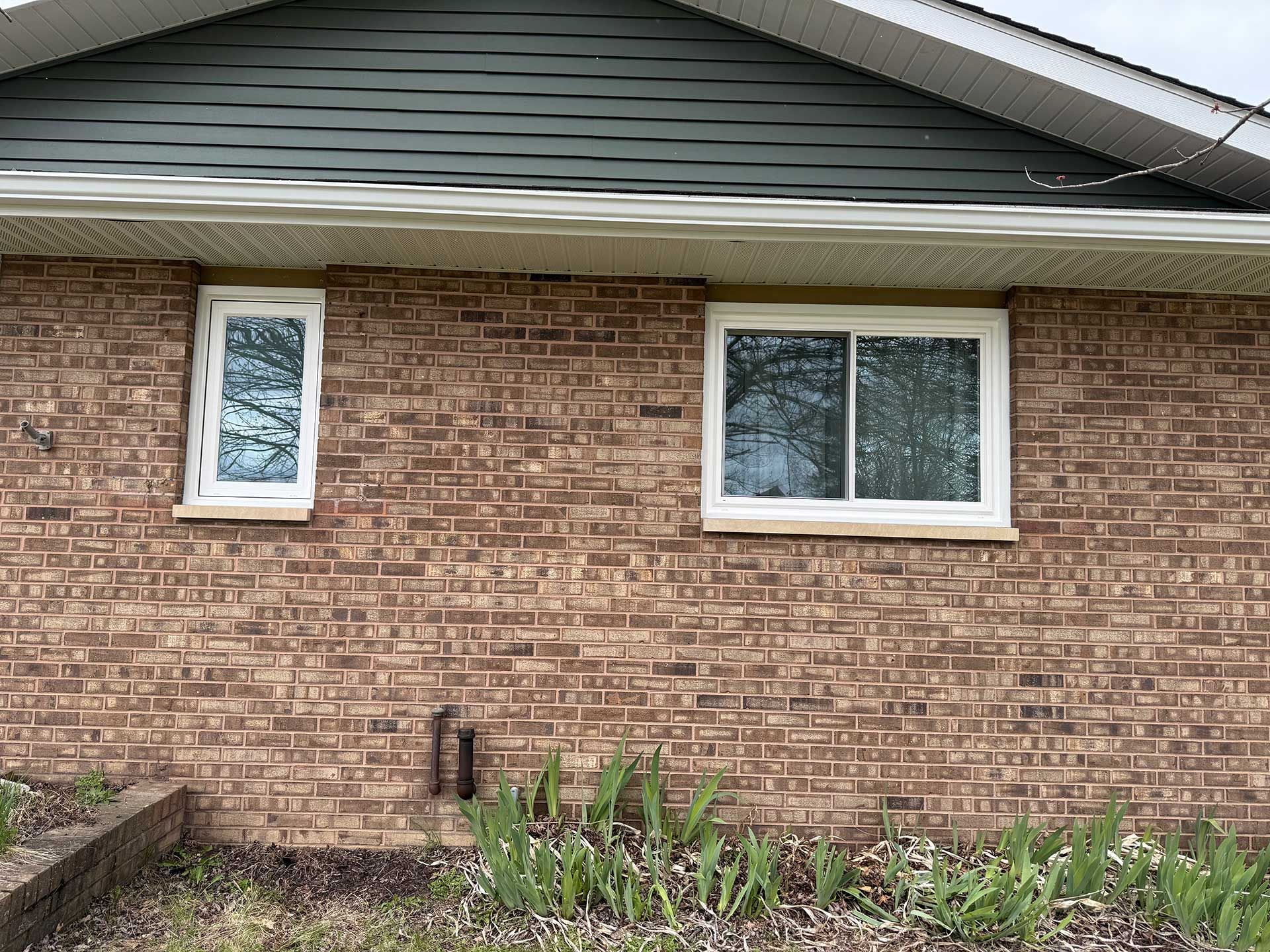 a brick house with two windows on the side of it