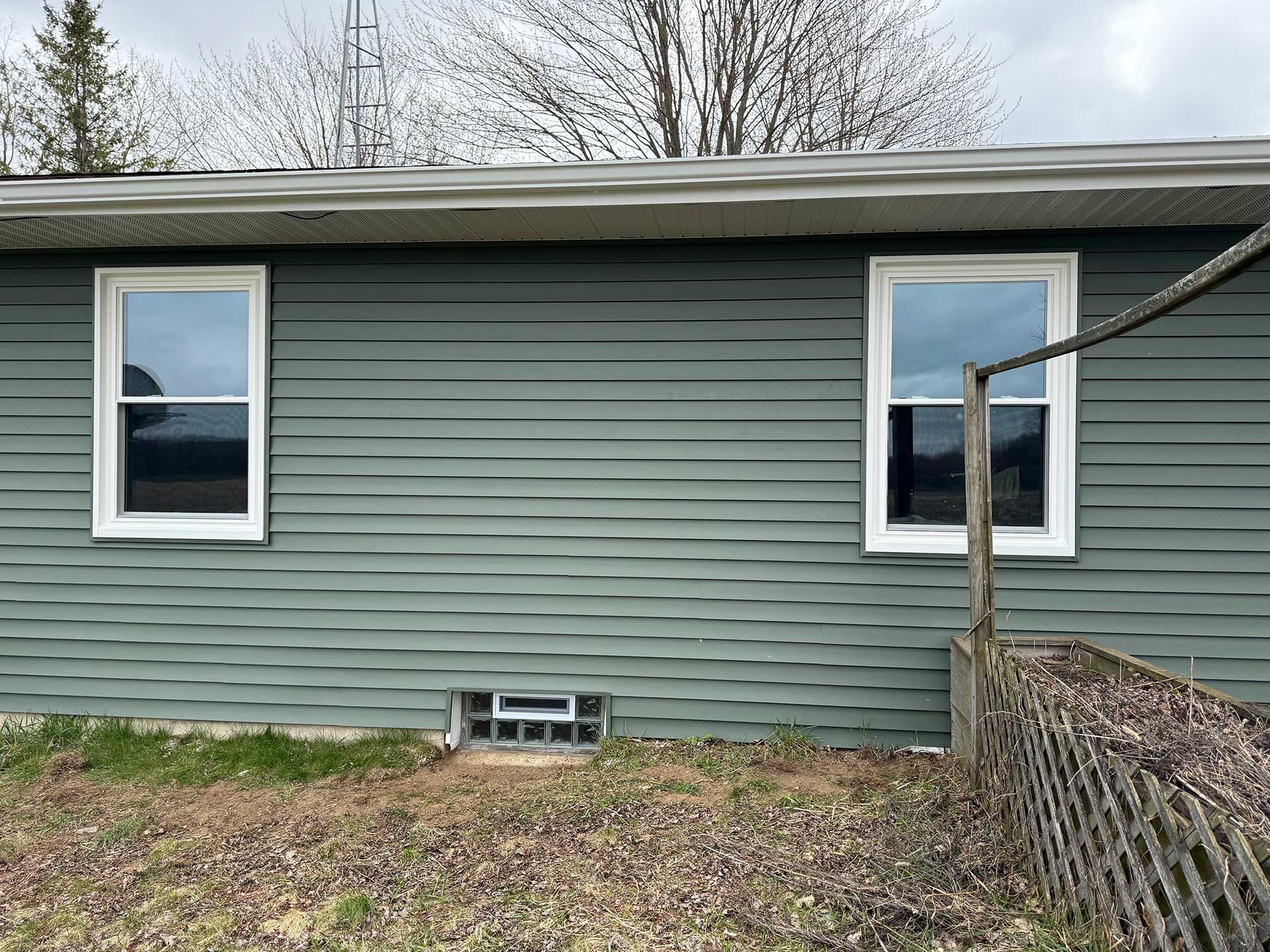 a house with two windows and a fence in front of it