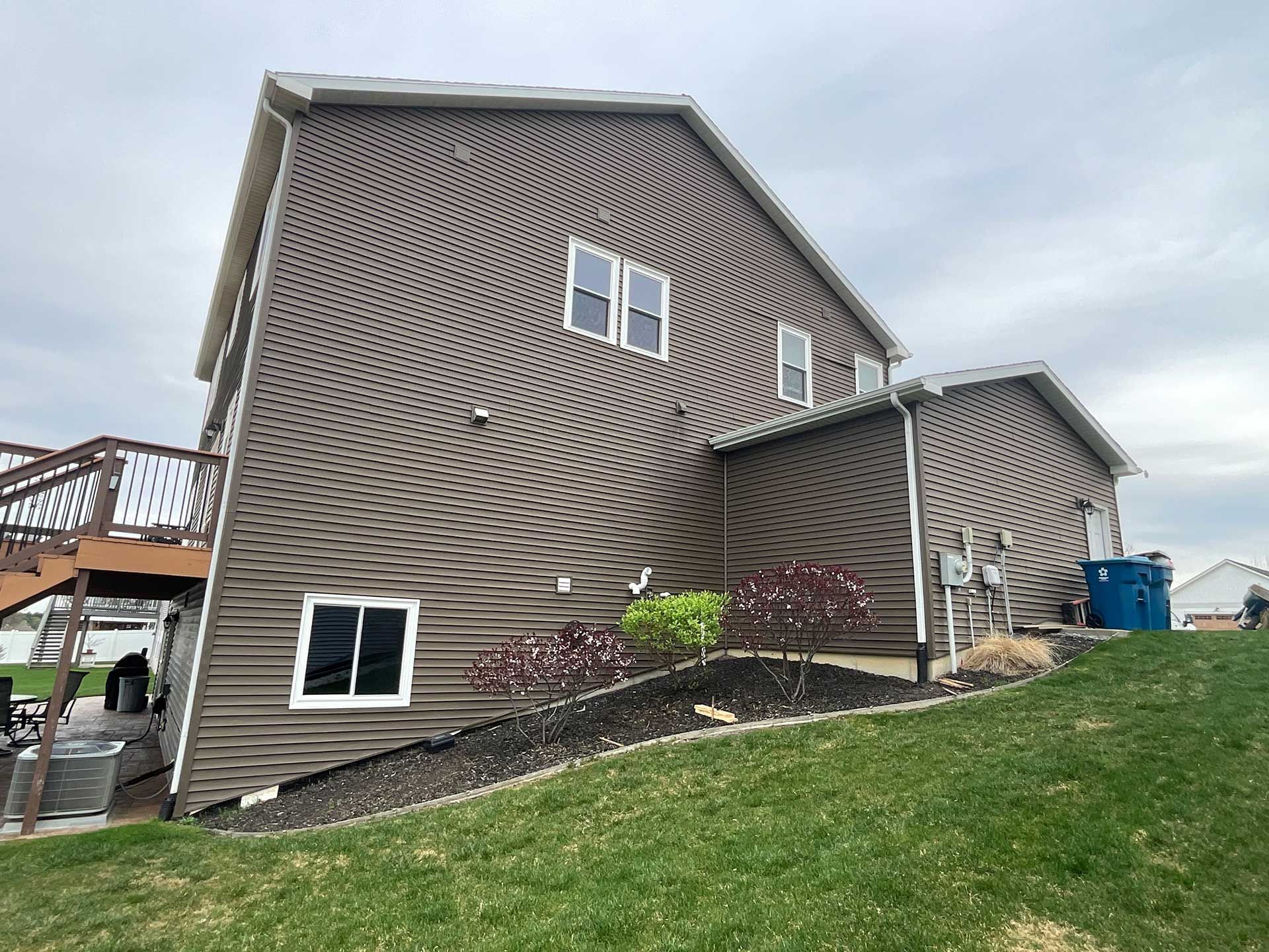 a large house with a lot of windows is sitting on top of a grassy hill