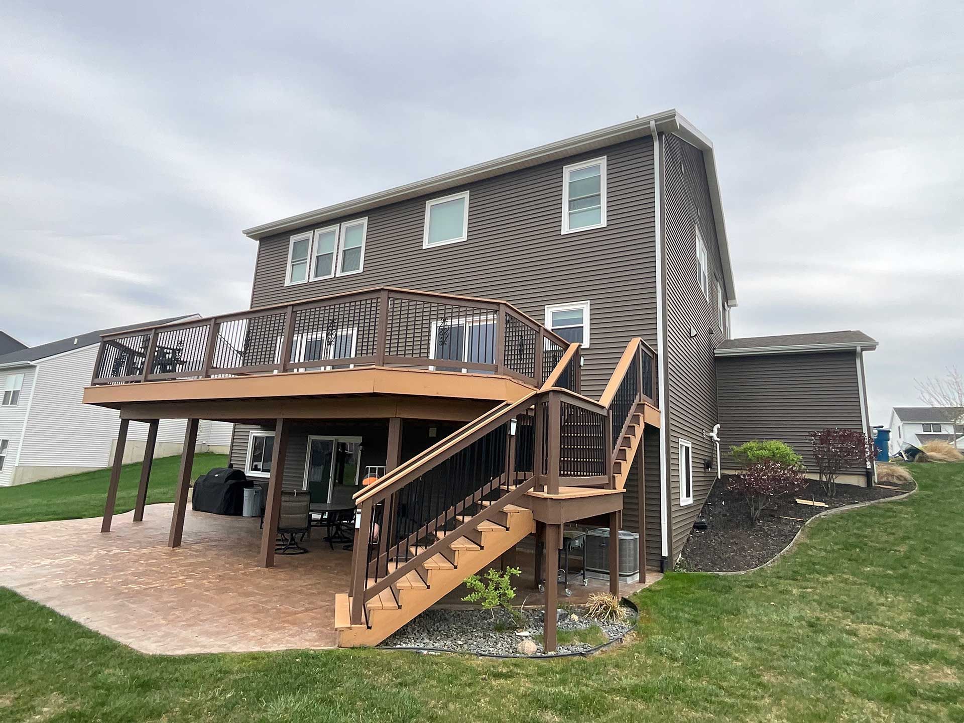 the back of a house with a large deck, patio, and stairs