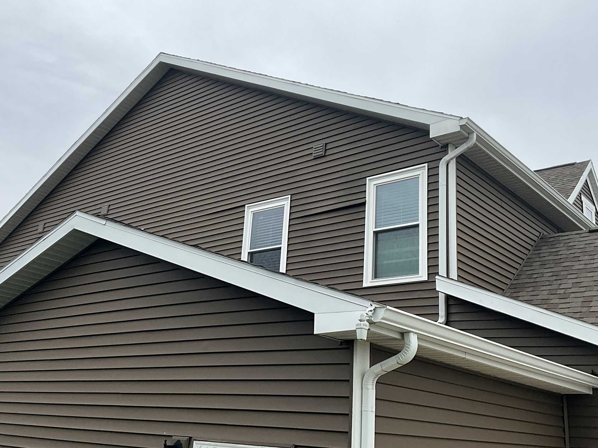 the roof of a brown house with white trim and windows