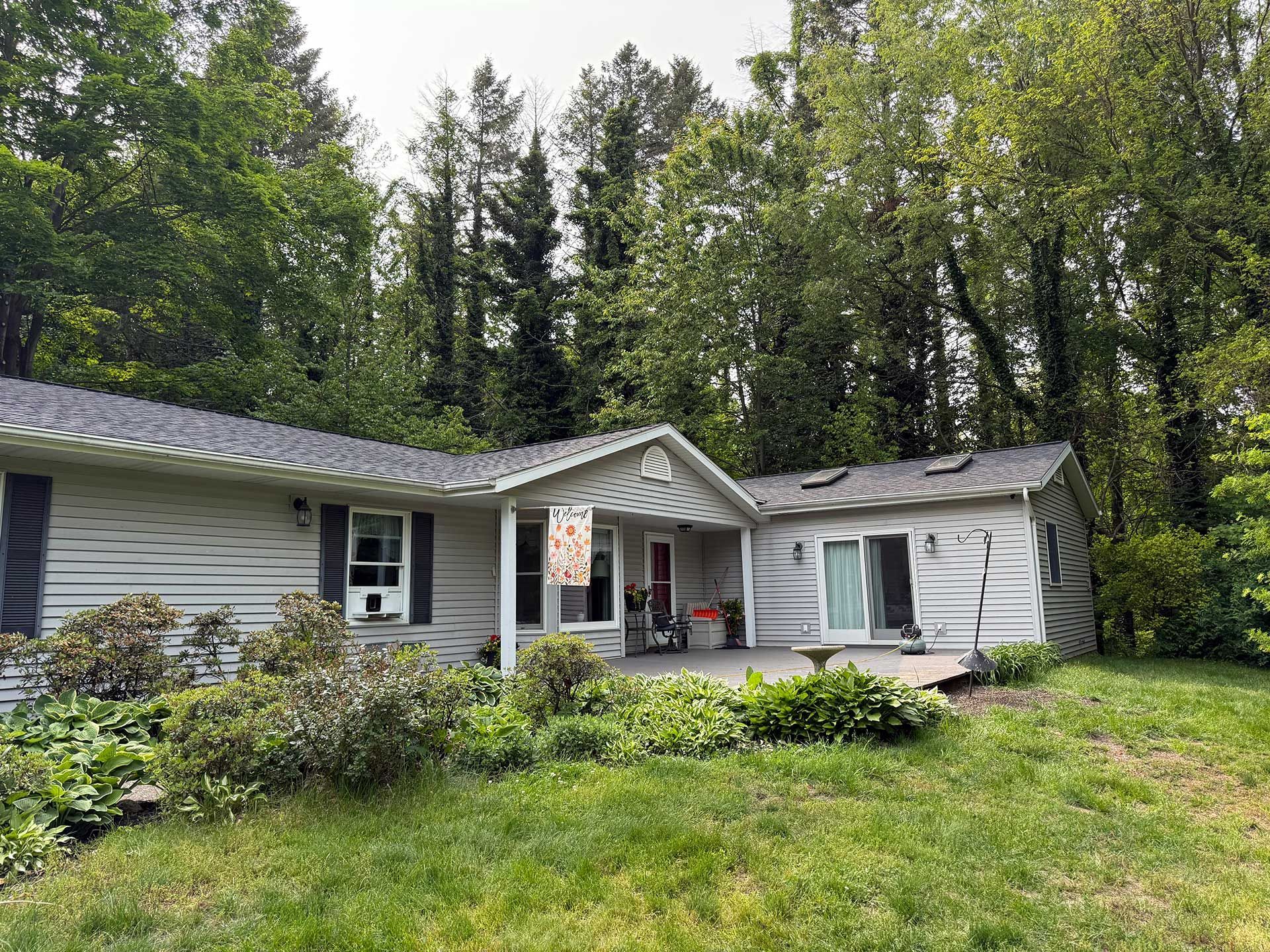 a white house with a large lawn in front of it is surrounded by trees