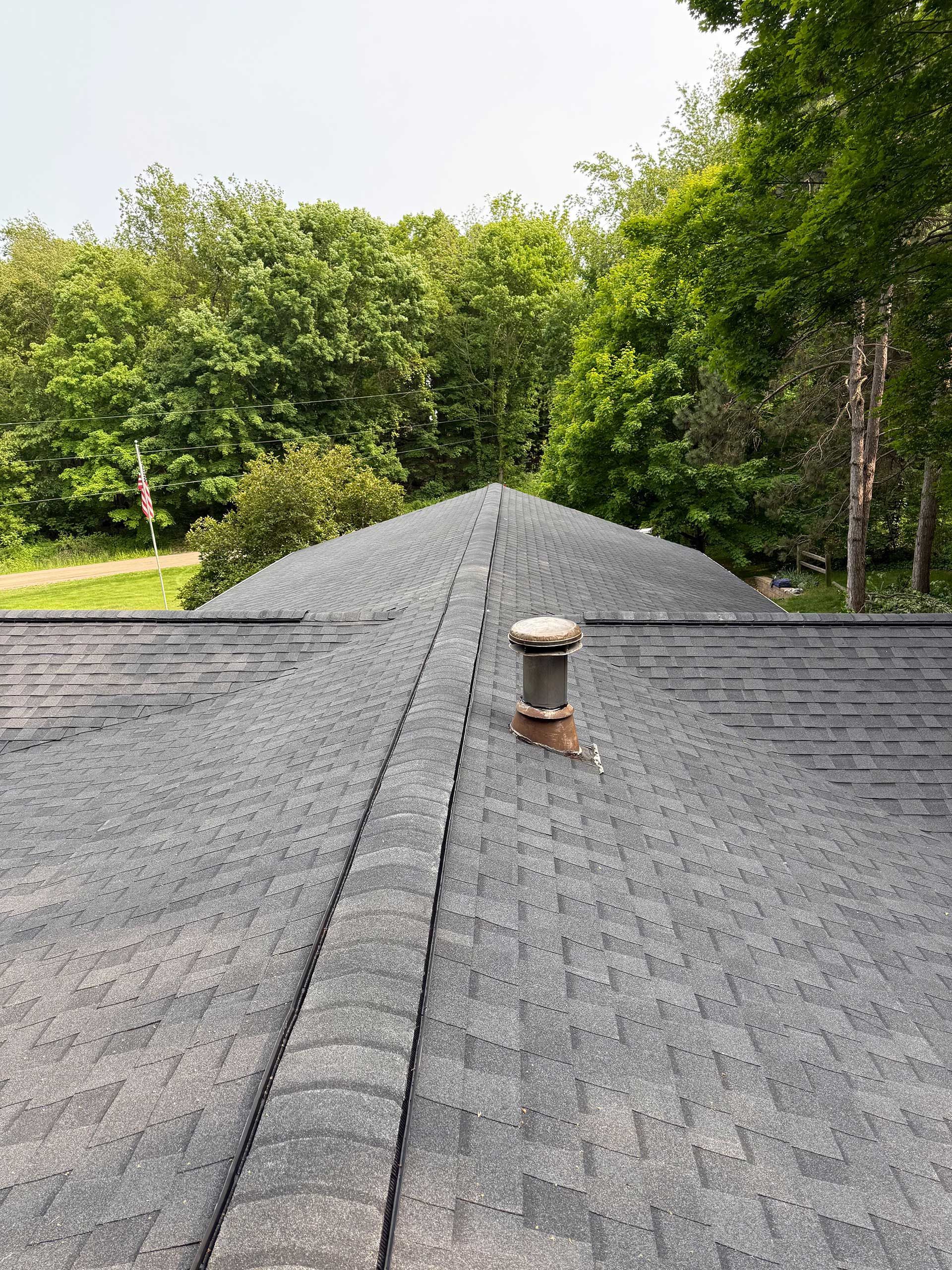a roof with a chimney on it and trees in the background
