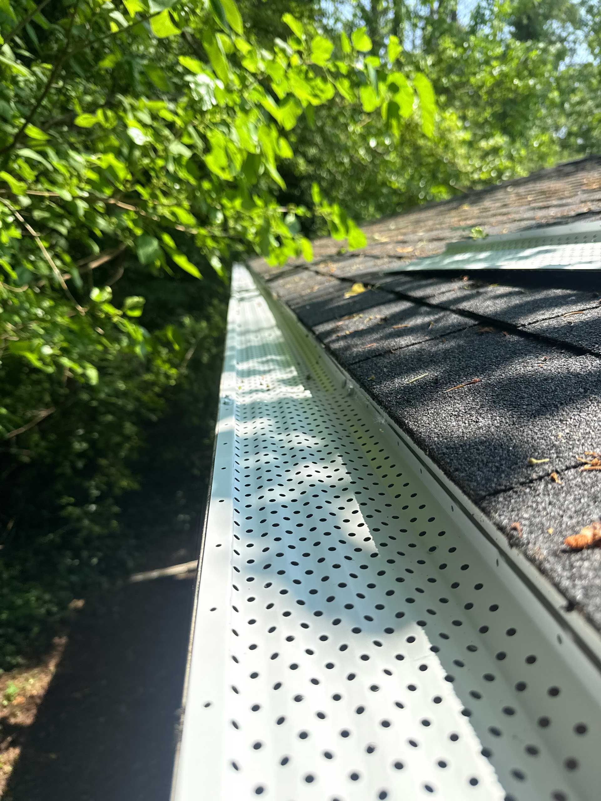 a close up of a gutter on a roof with trees in the background