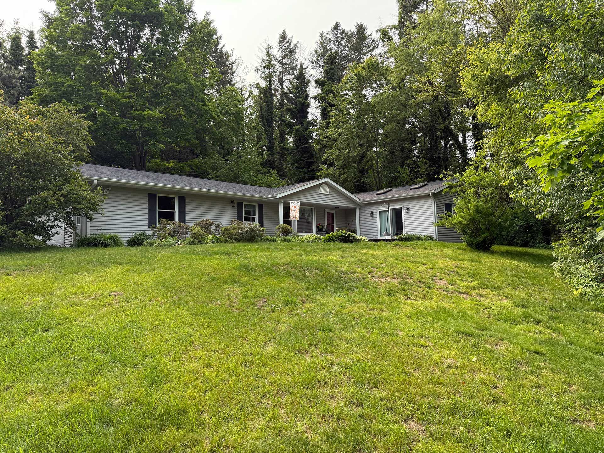a house with a large lawn is surrounded by trees