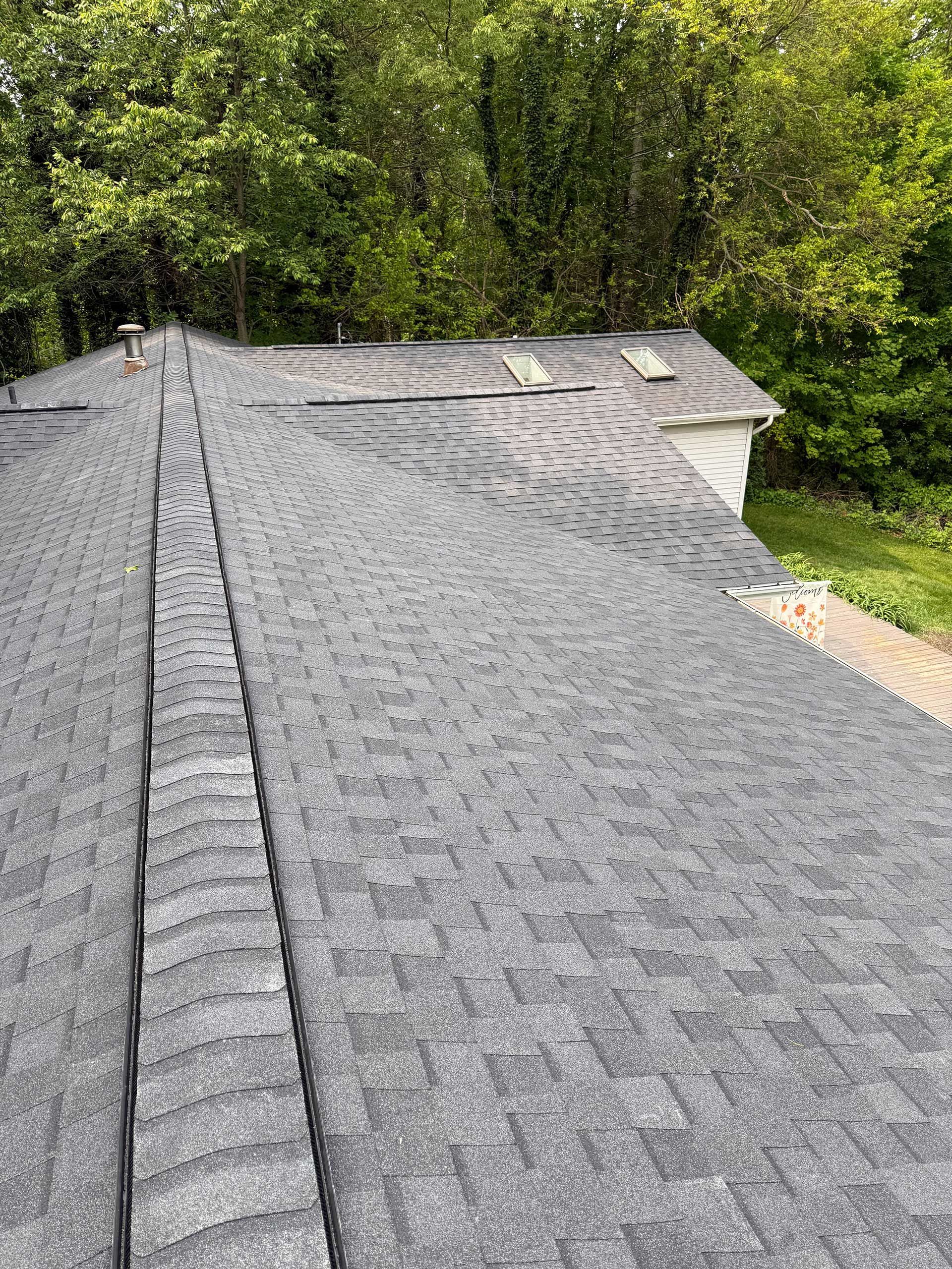 a roof with a lot of shingles on it is surrounded by trees