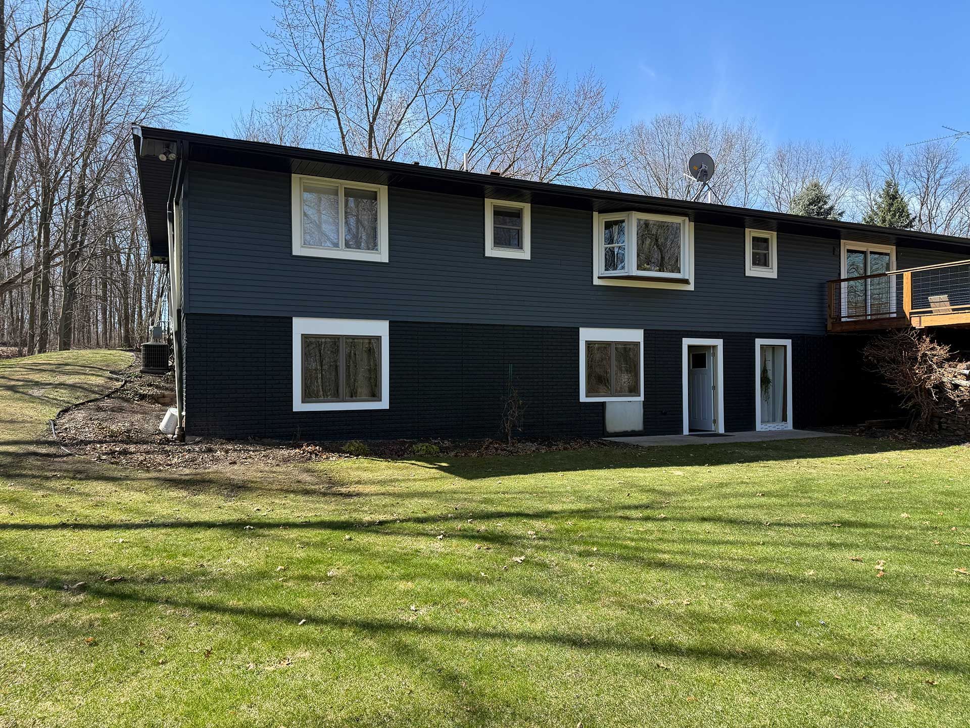a black house with white trim is sitting on top of a lush green field