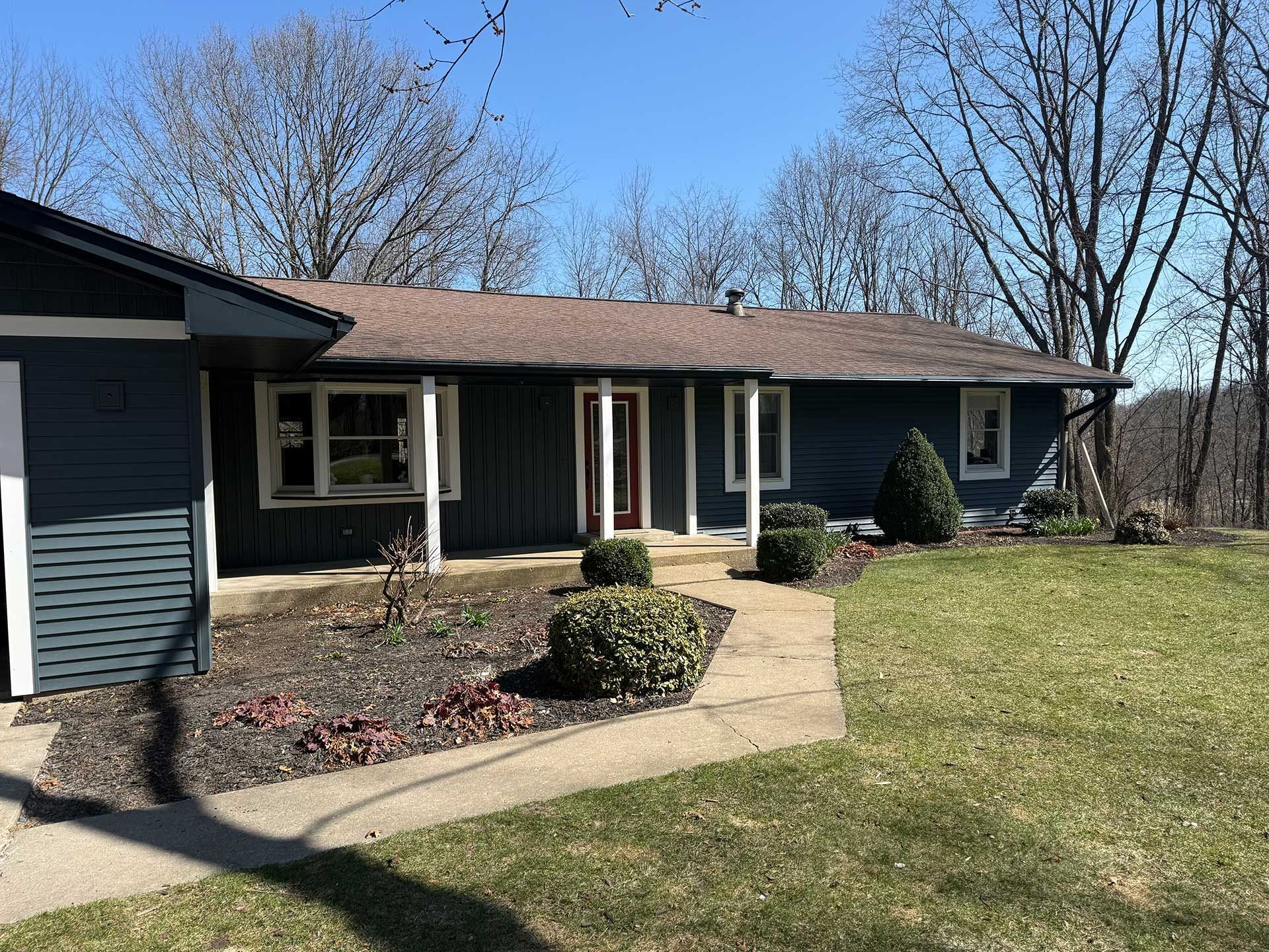 a blue house with a brown roof and a walkway leading to it