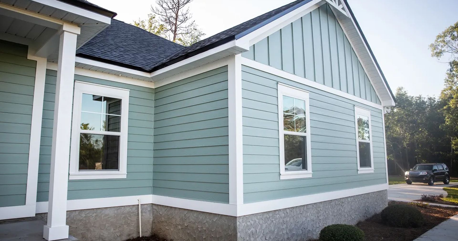 A blue and white house with a car parked in front of it.