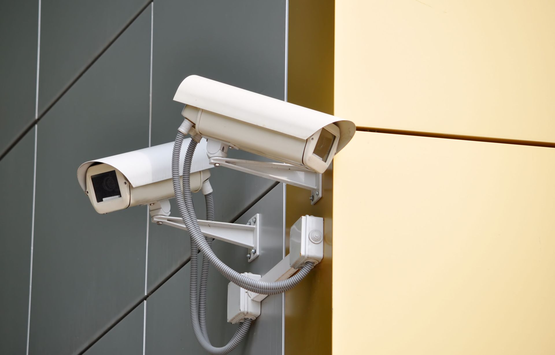 Two white security cameras mounted on a building wall.