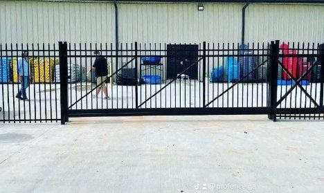 A man is standing behind a black fence in front of a building