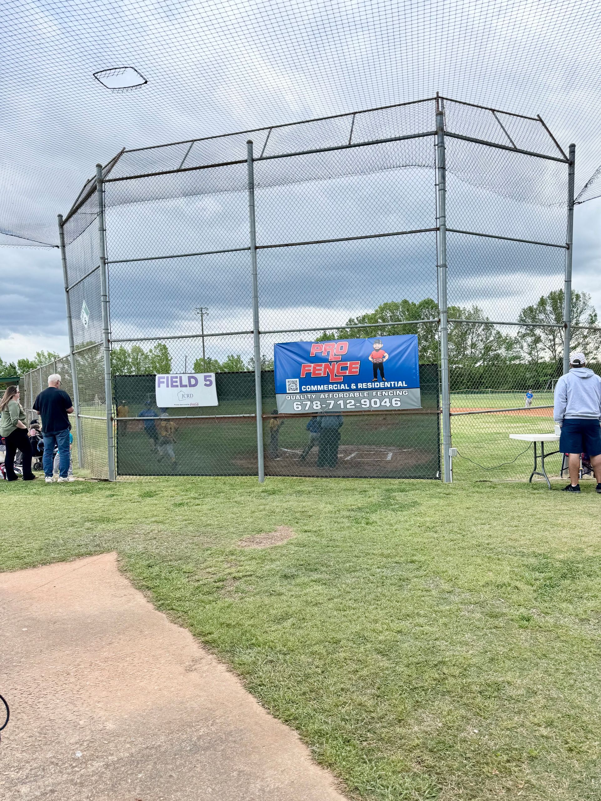 A baseball cage with a sign on it in a park