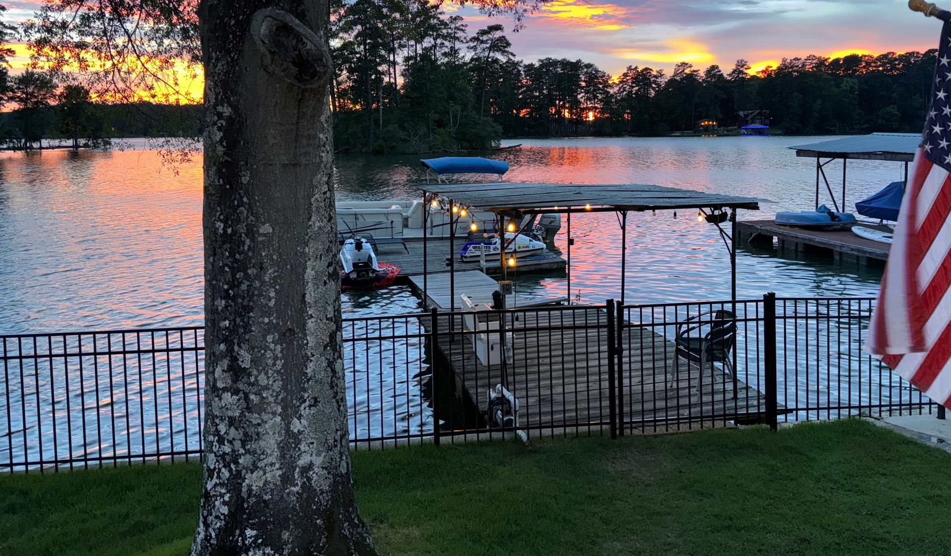 An American flag is flying in front of a lake at sunset