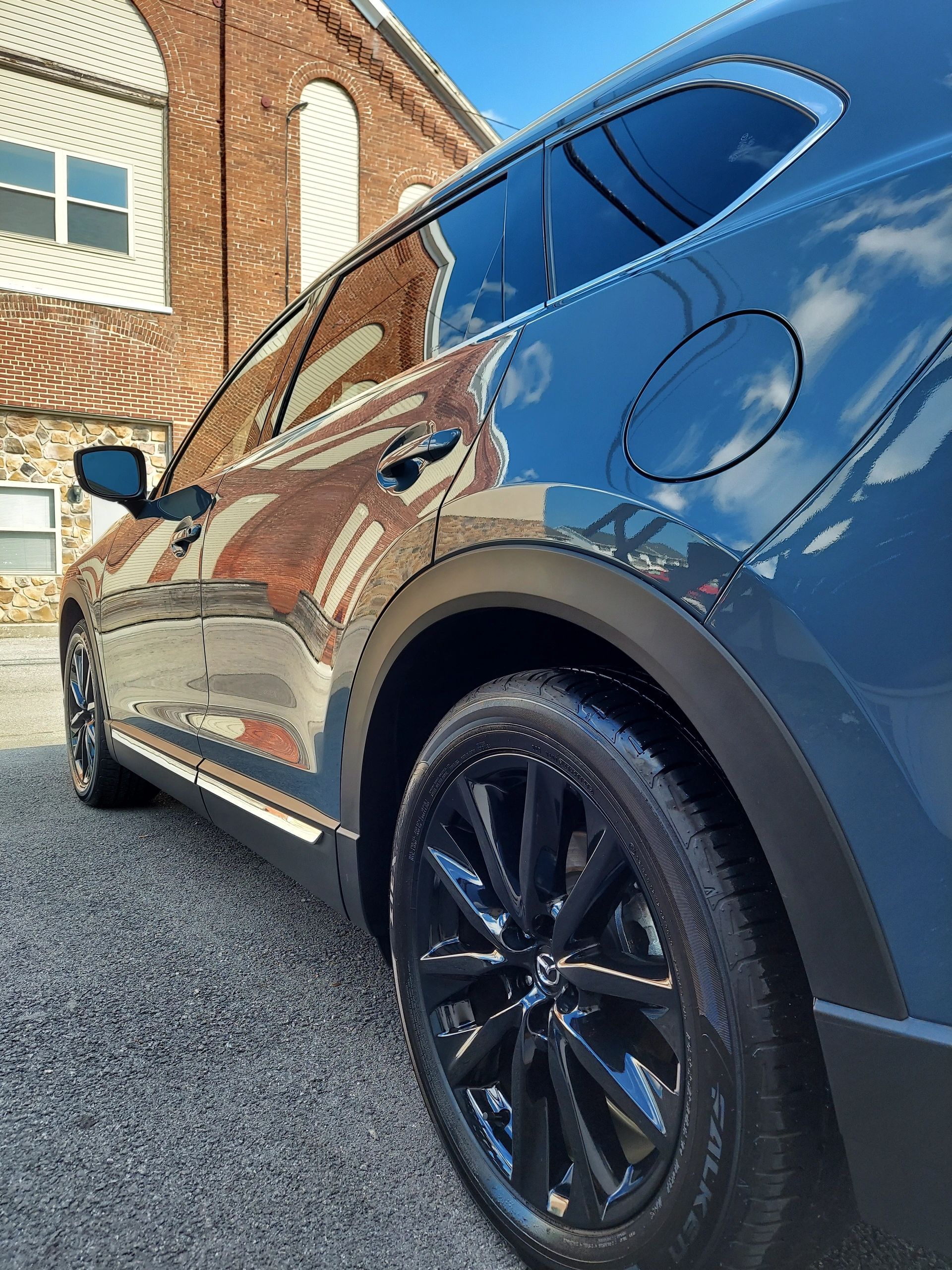 A black car is parked in front of a brick building.