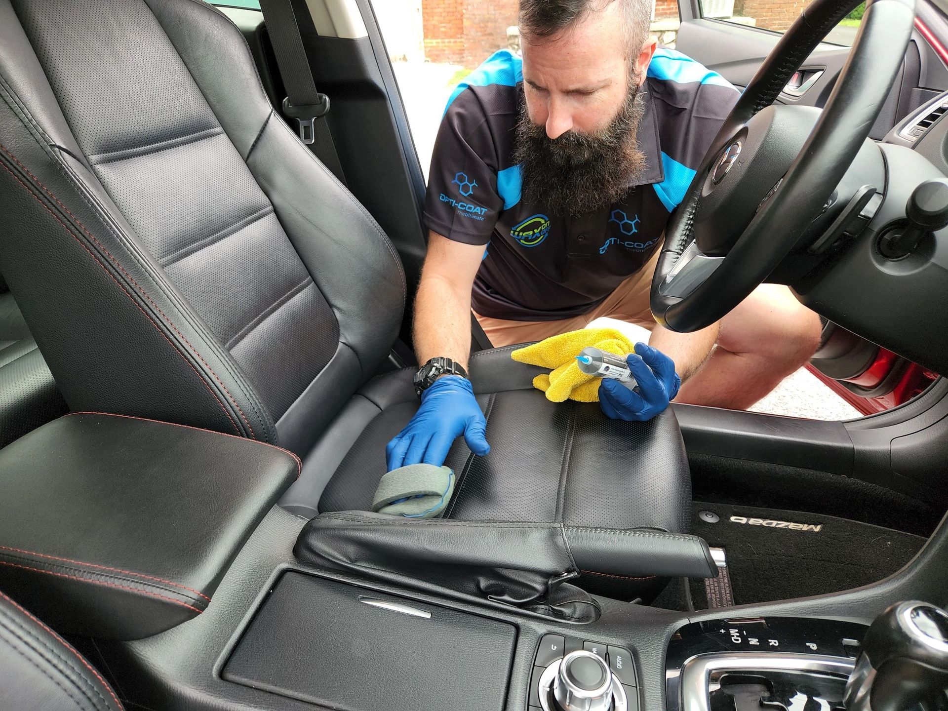 A man with a beard is cleaning the seats of a car.