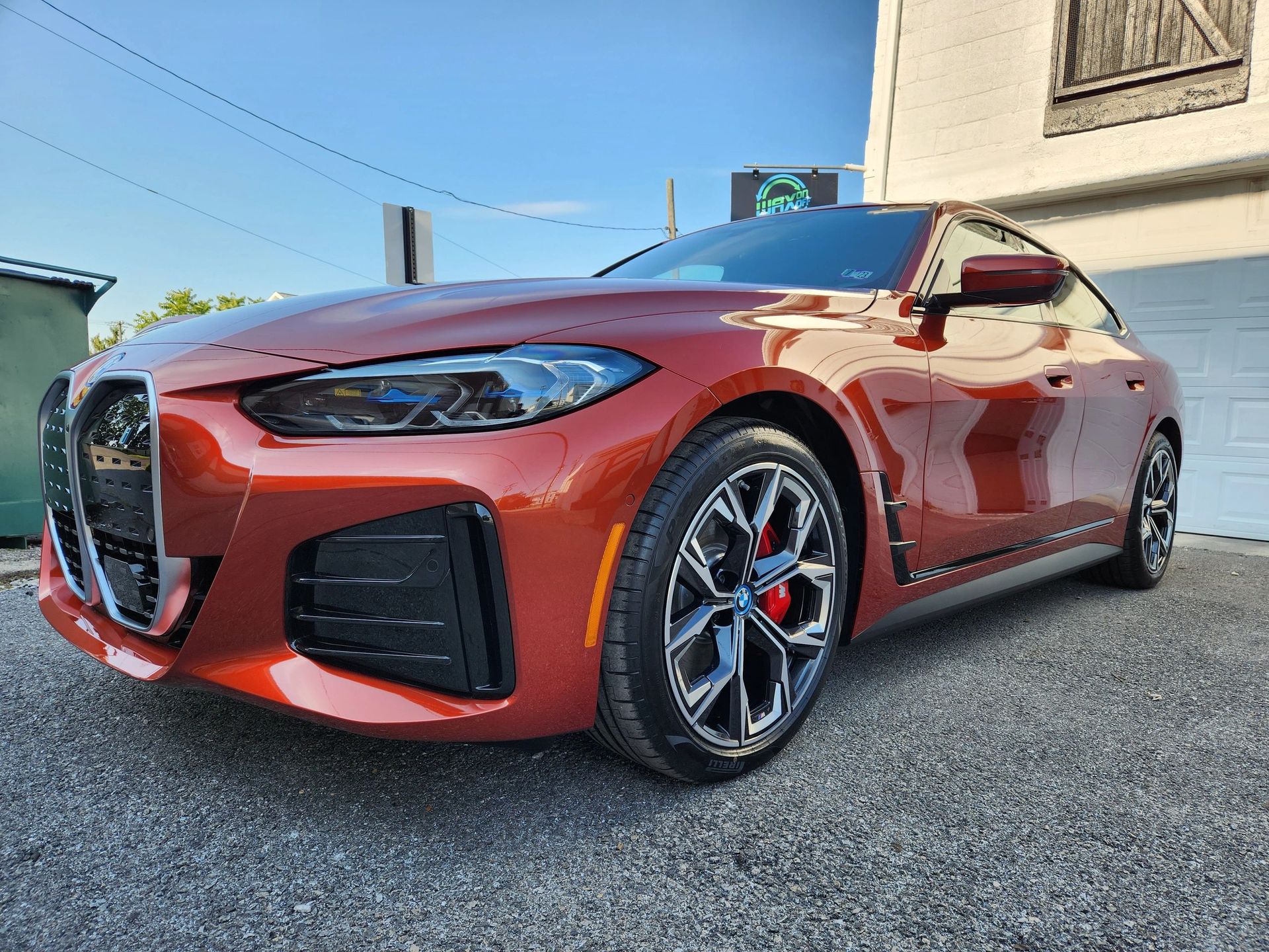 A red bmw 4 series is parked in front of a garage door.