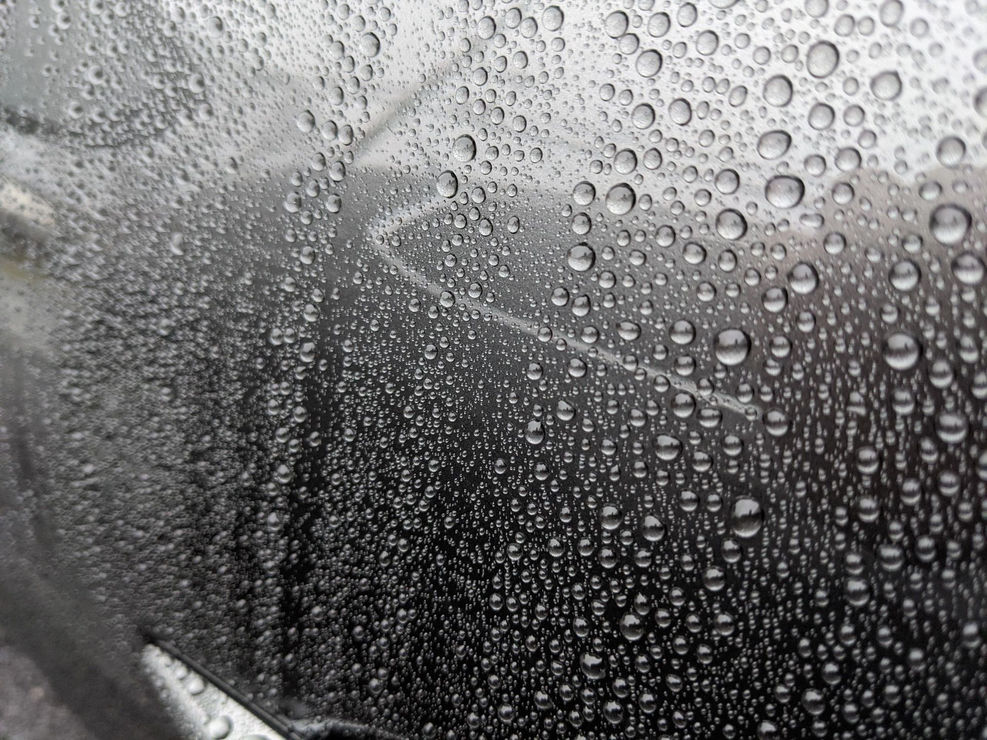 A close up of rain drops on a car windshield.