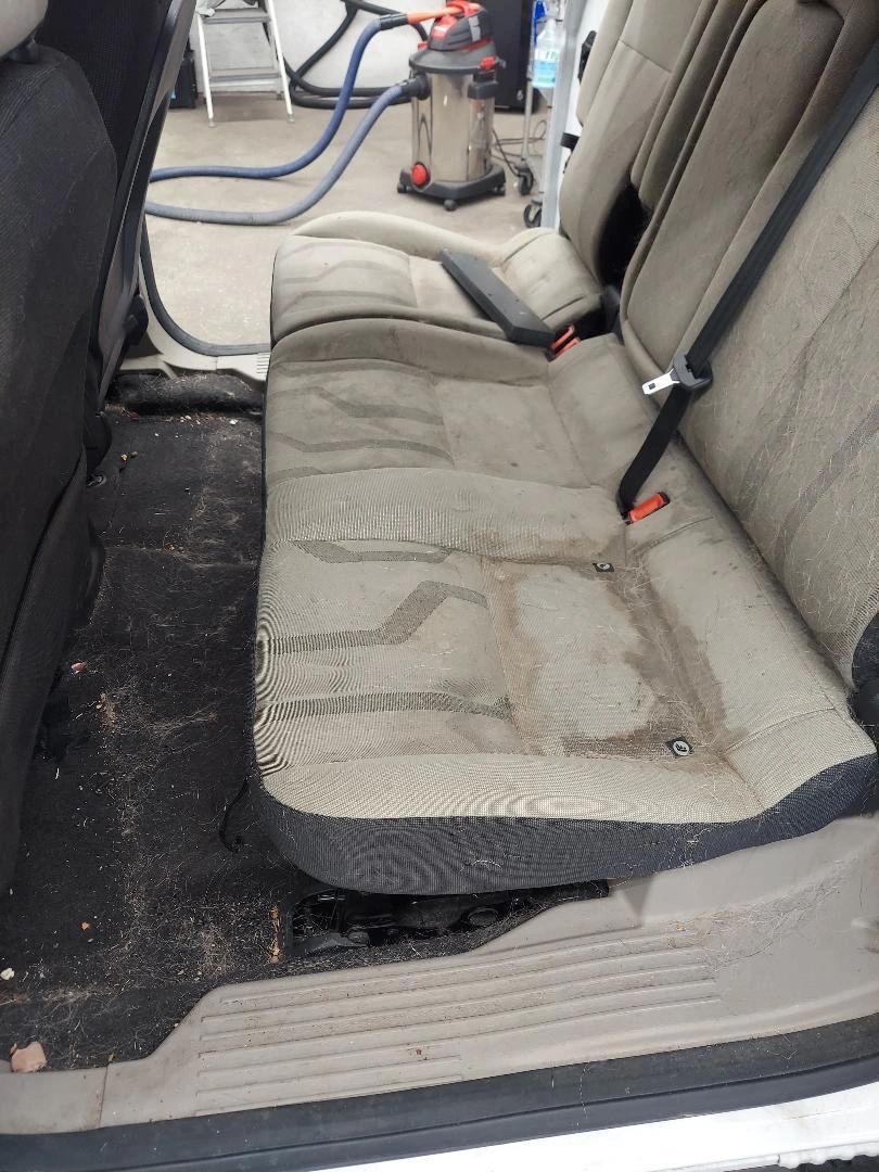 The back seat of a car is dirty and needs to be cleaned.