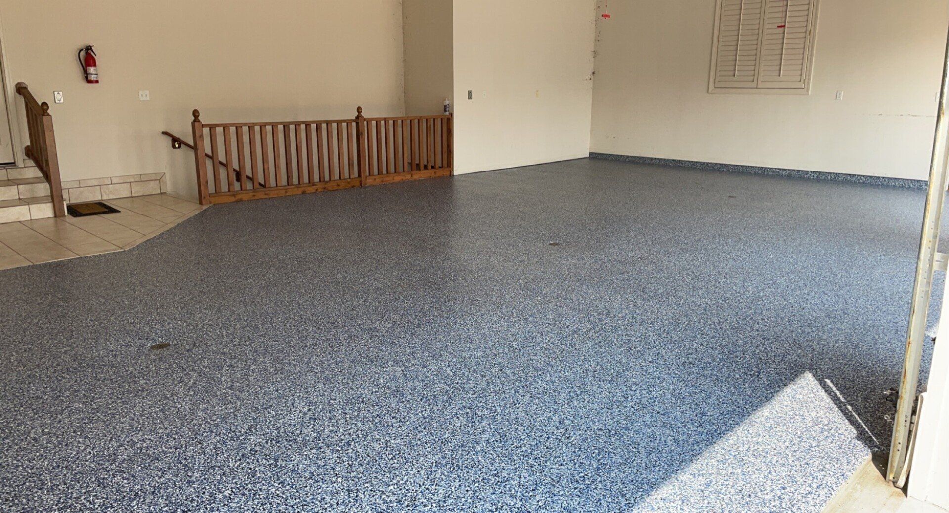 Garage interior with a gray speckled epoxy floor and wooden railing.
