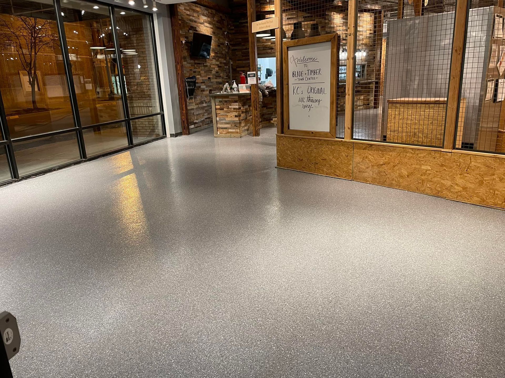 A shiny, speckled floor in a room with wood and glass walls.