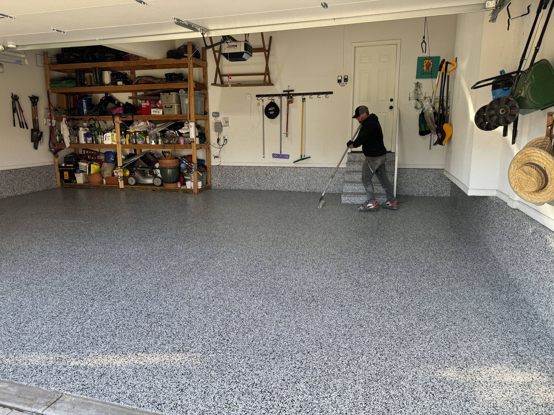Garage with epoxy floor, shelving, and a person using a step stool.
