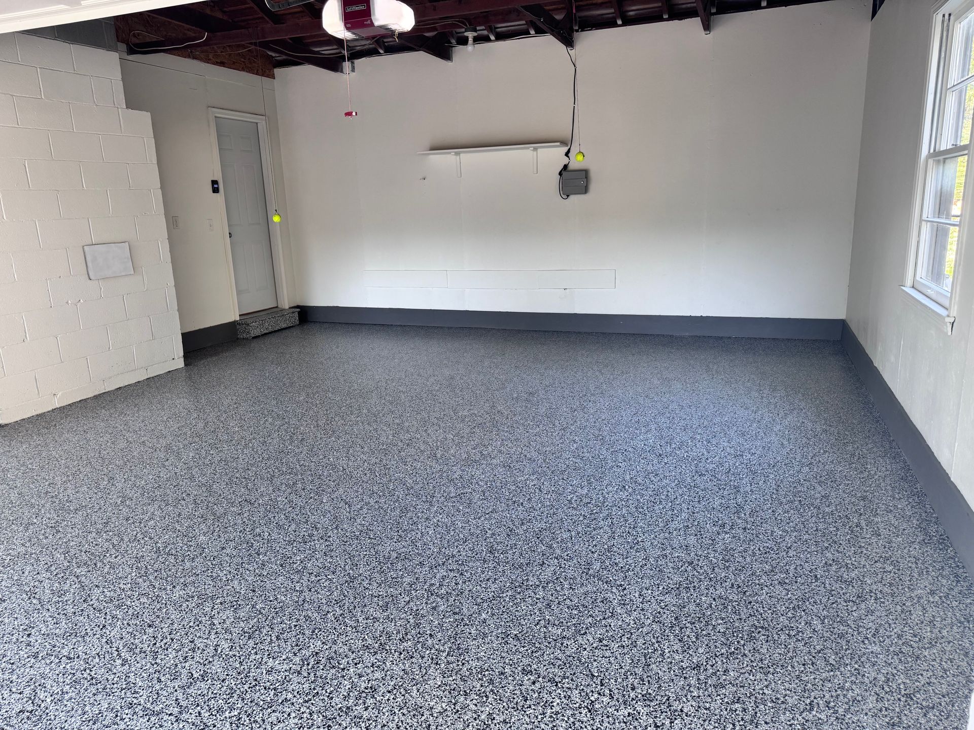 Garage with epoxy floor, white walls, and a closed door.