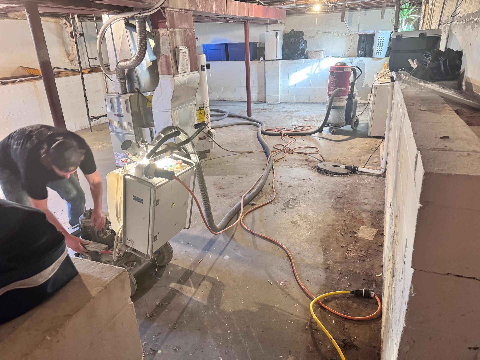 Person operating machinery in a basement with debris and insulation.