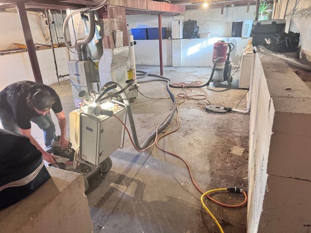 Person operating machinery in a basement with debris and insulation.