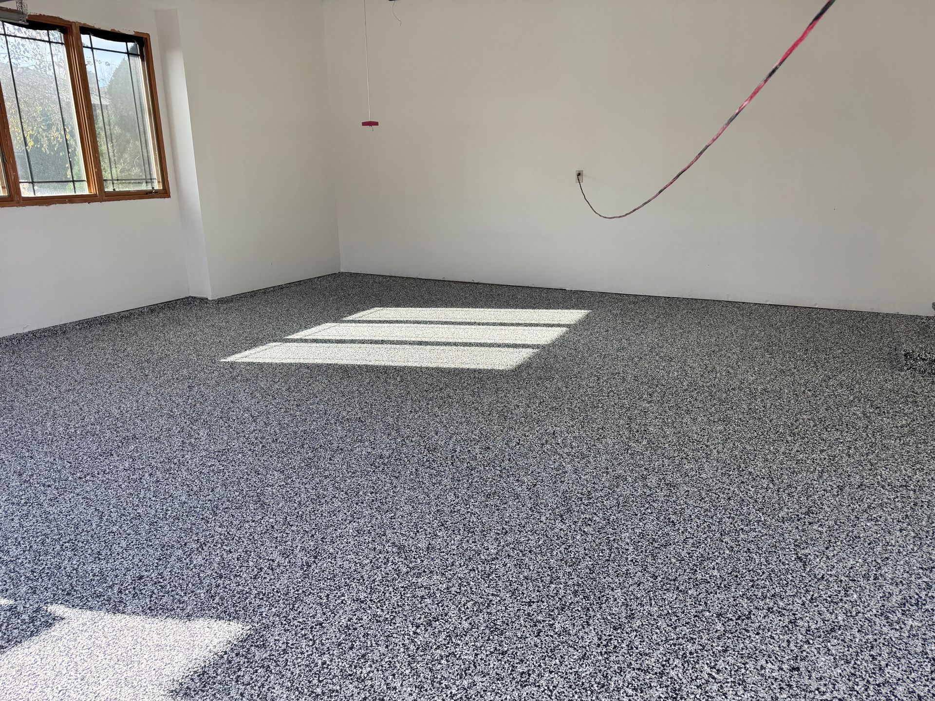 Room with gray pebble floor; white walls, sunlight from window.