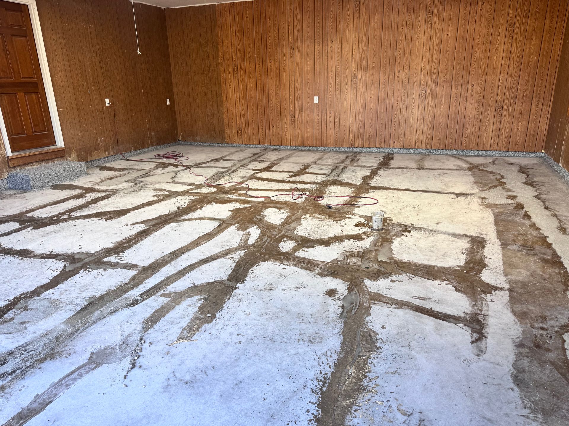 Concrete floor with grooves cut into it, brown wood paneled walls.