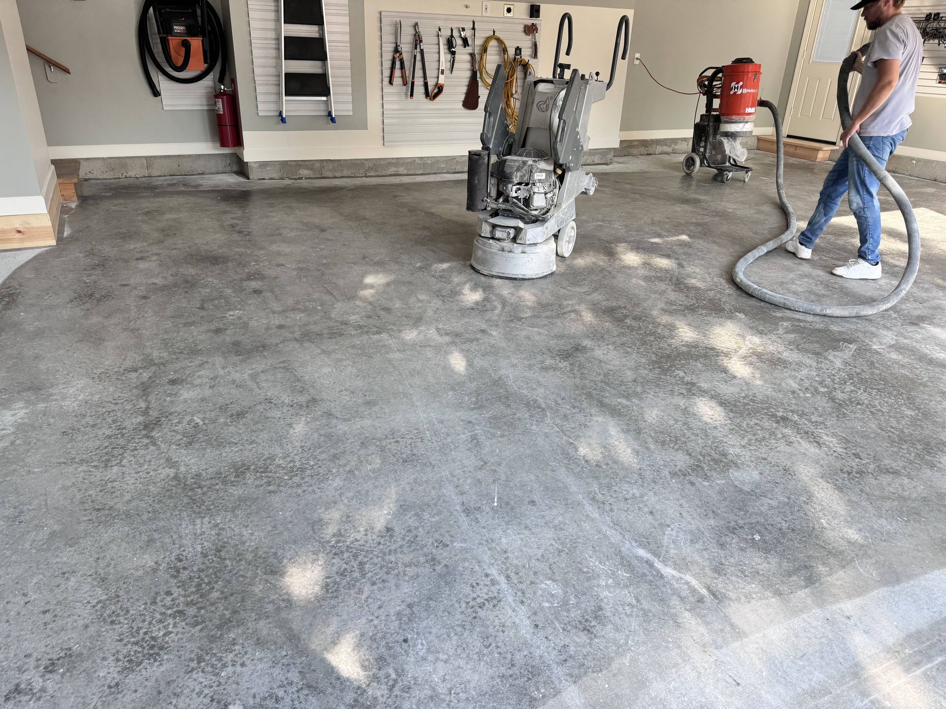 Person grinding a concrete garage floor with industrial equipment.