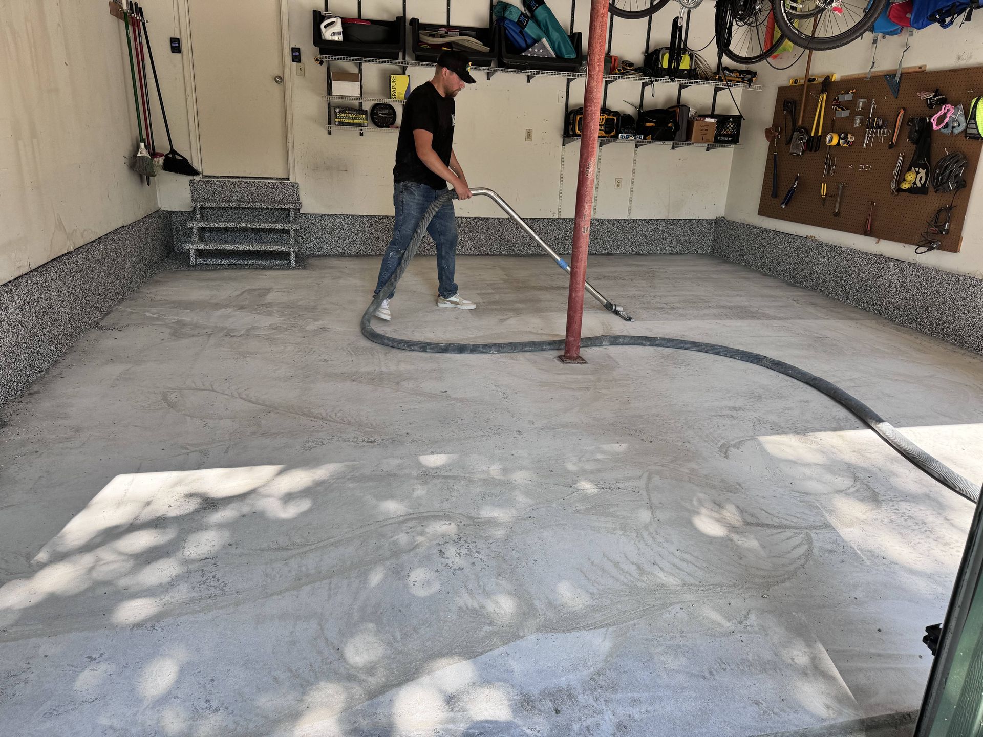 Man vacuuming a garage floor with a gray epoxy coating.