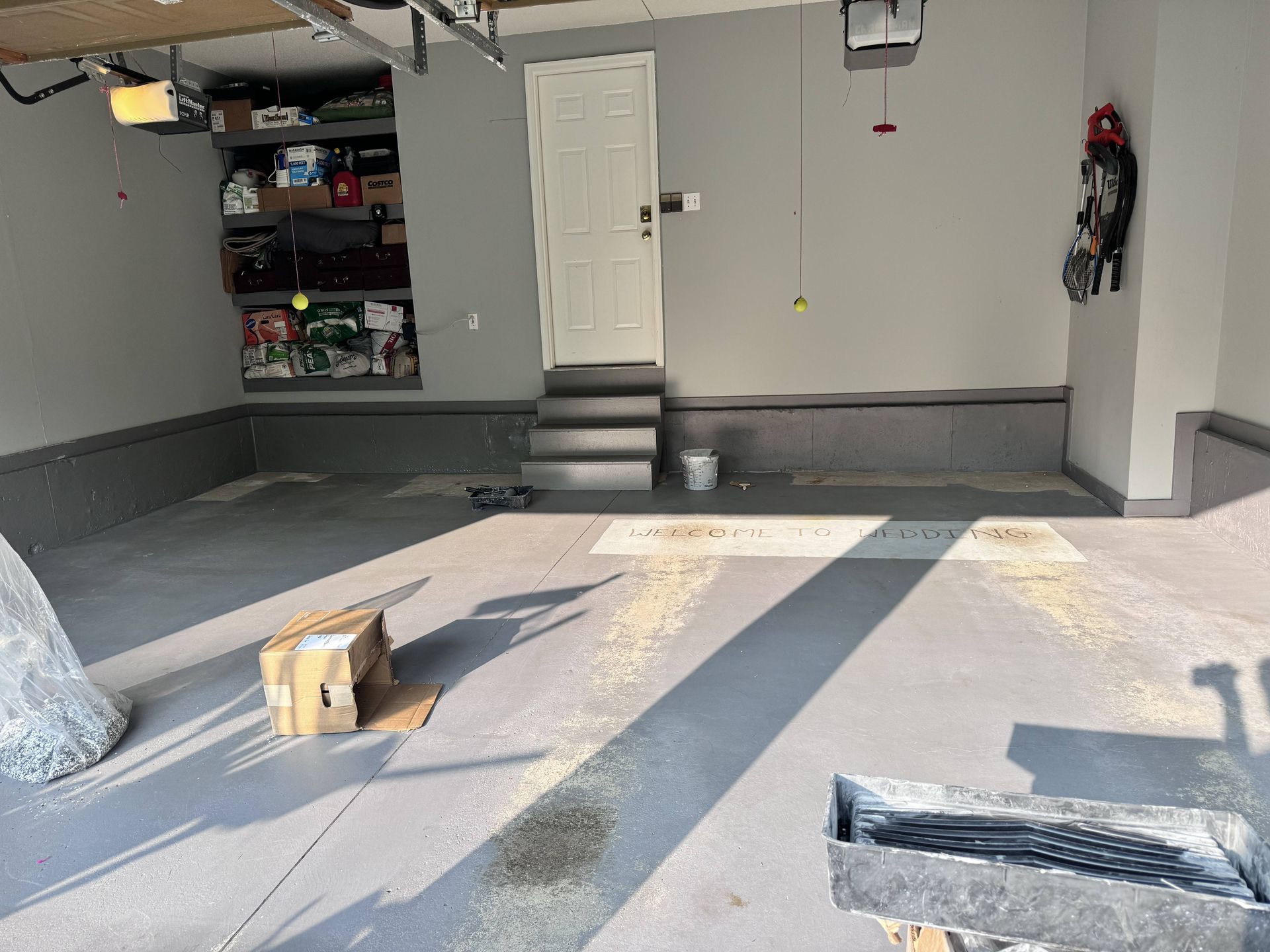 Garage interior with gray epoxy floor, white door, and storage shelves.