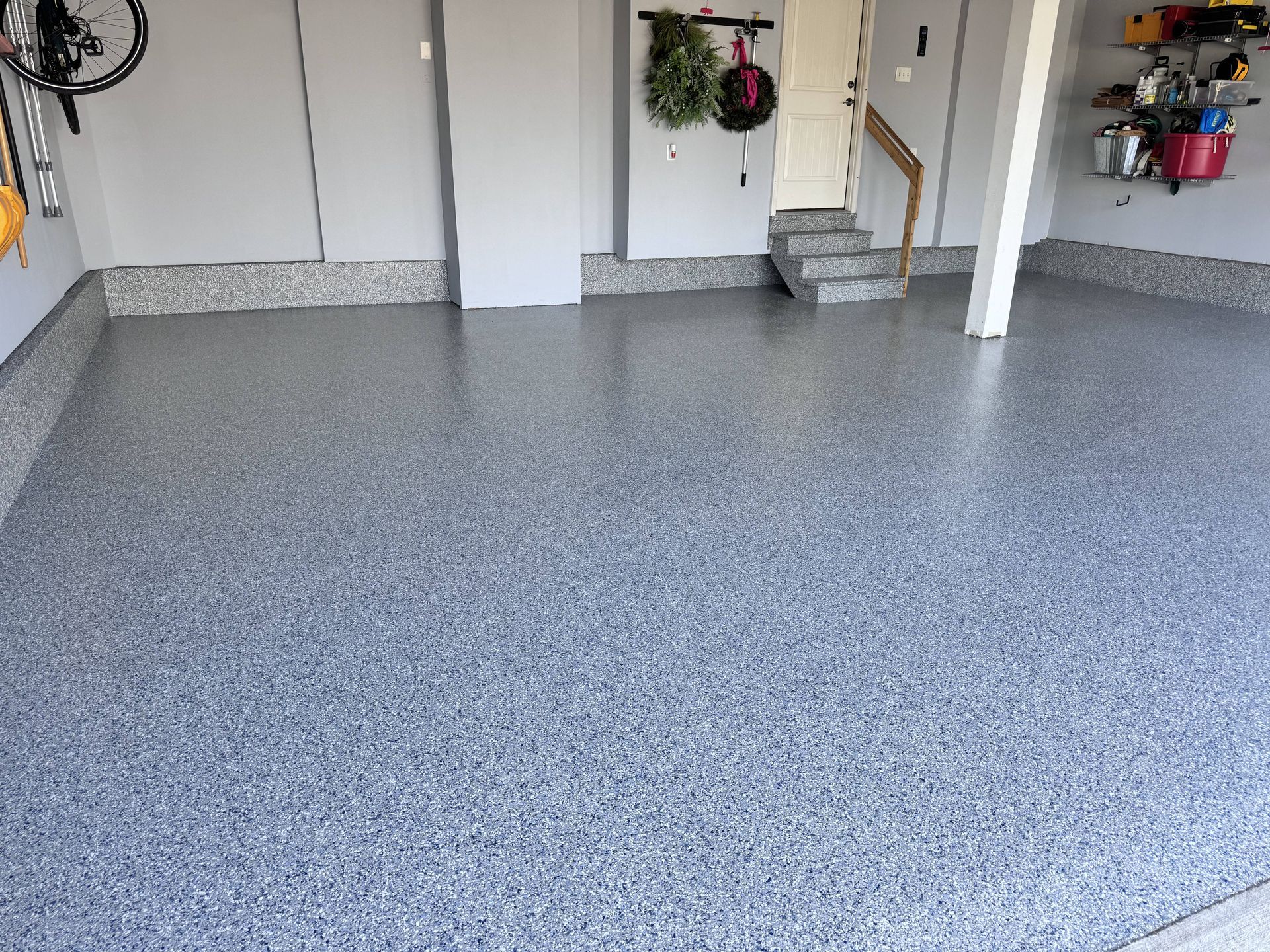 Garage with gray and black speckled epoxy floor, gray walls, and equipment.