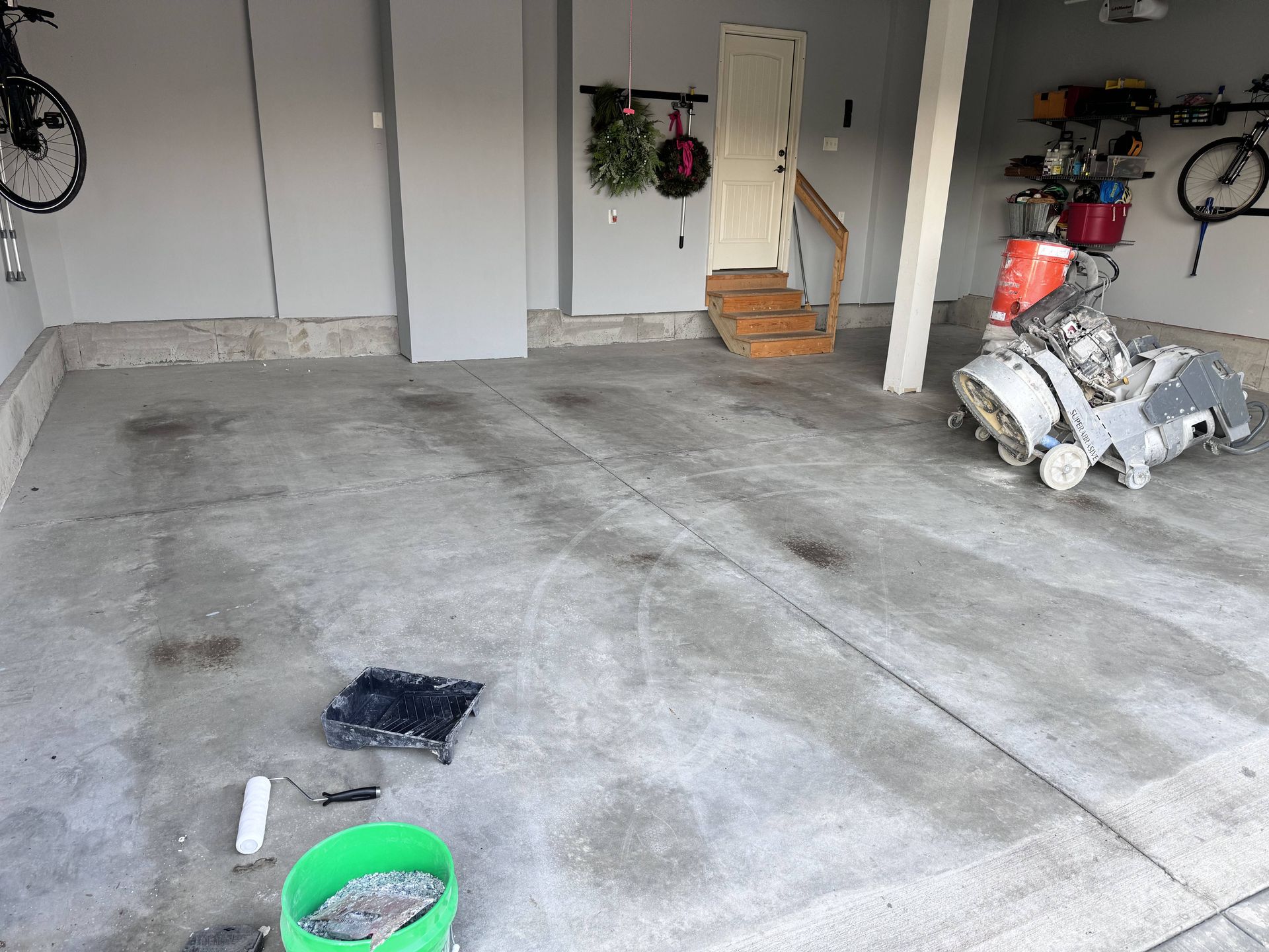 Garage with concrete floor, grinder, and bicycle on the wall.