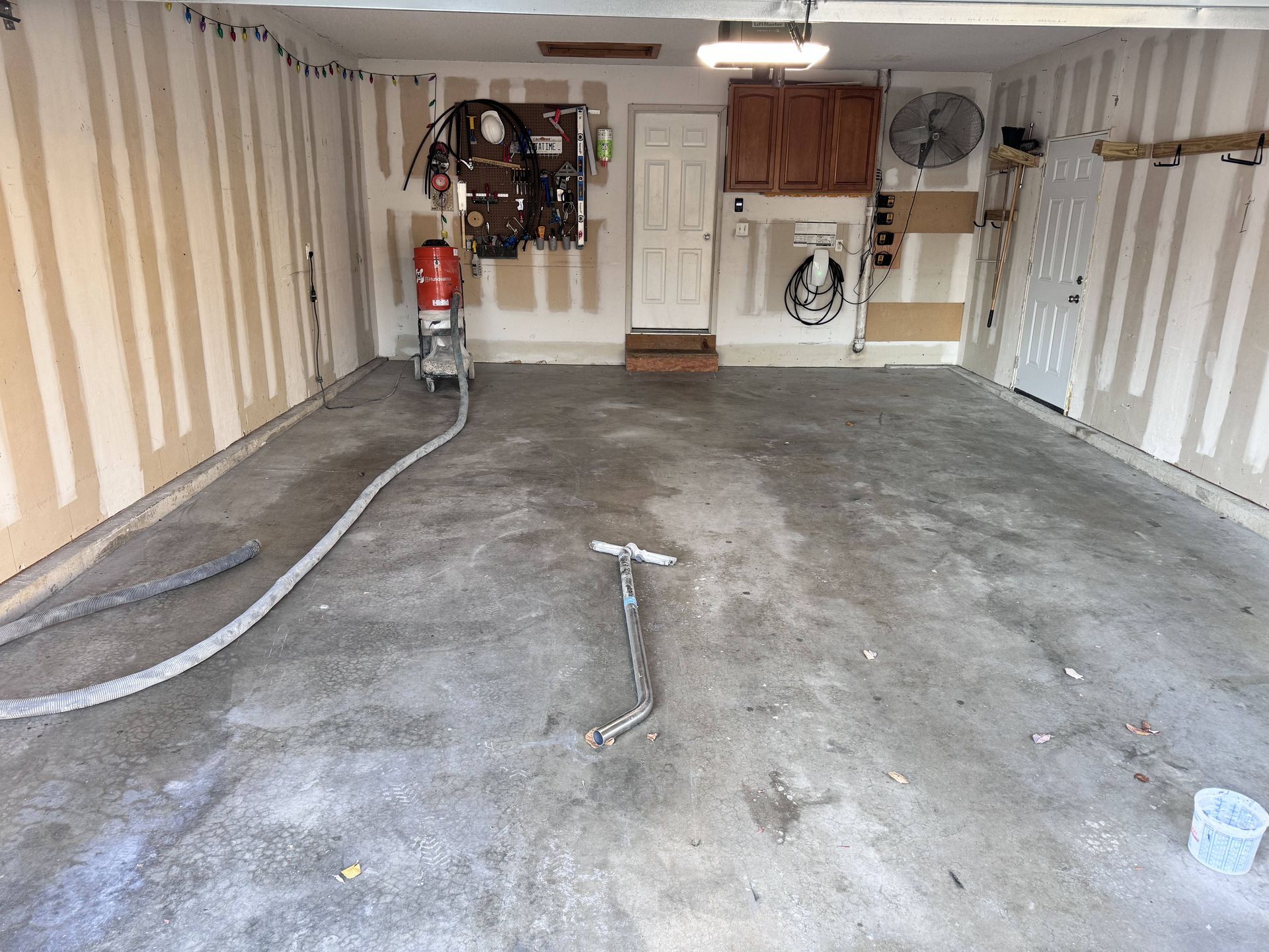 Garage interior with concrete floor, walls, and tools.  Abrasive blasting equipment is present.