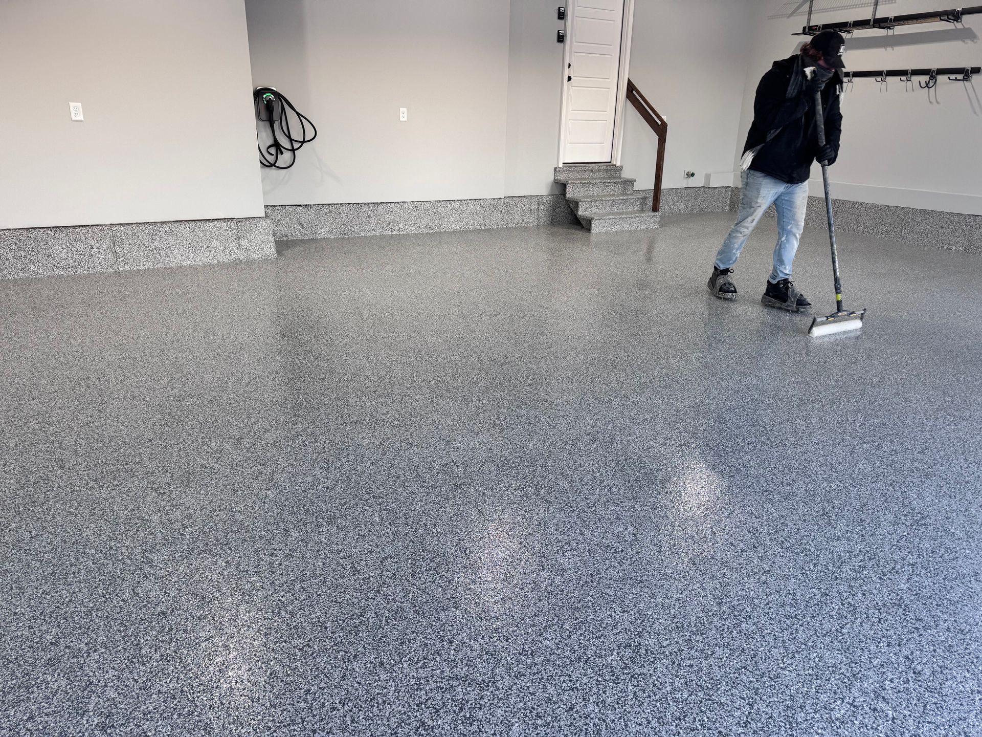 Person cleaning a garage floor with a decorative, speckled epoxy coating.