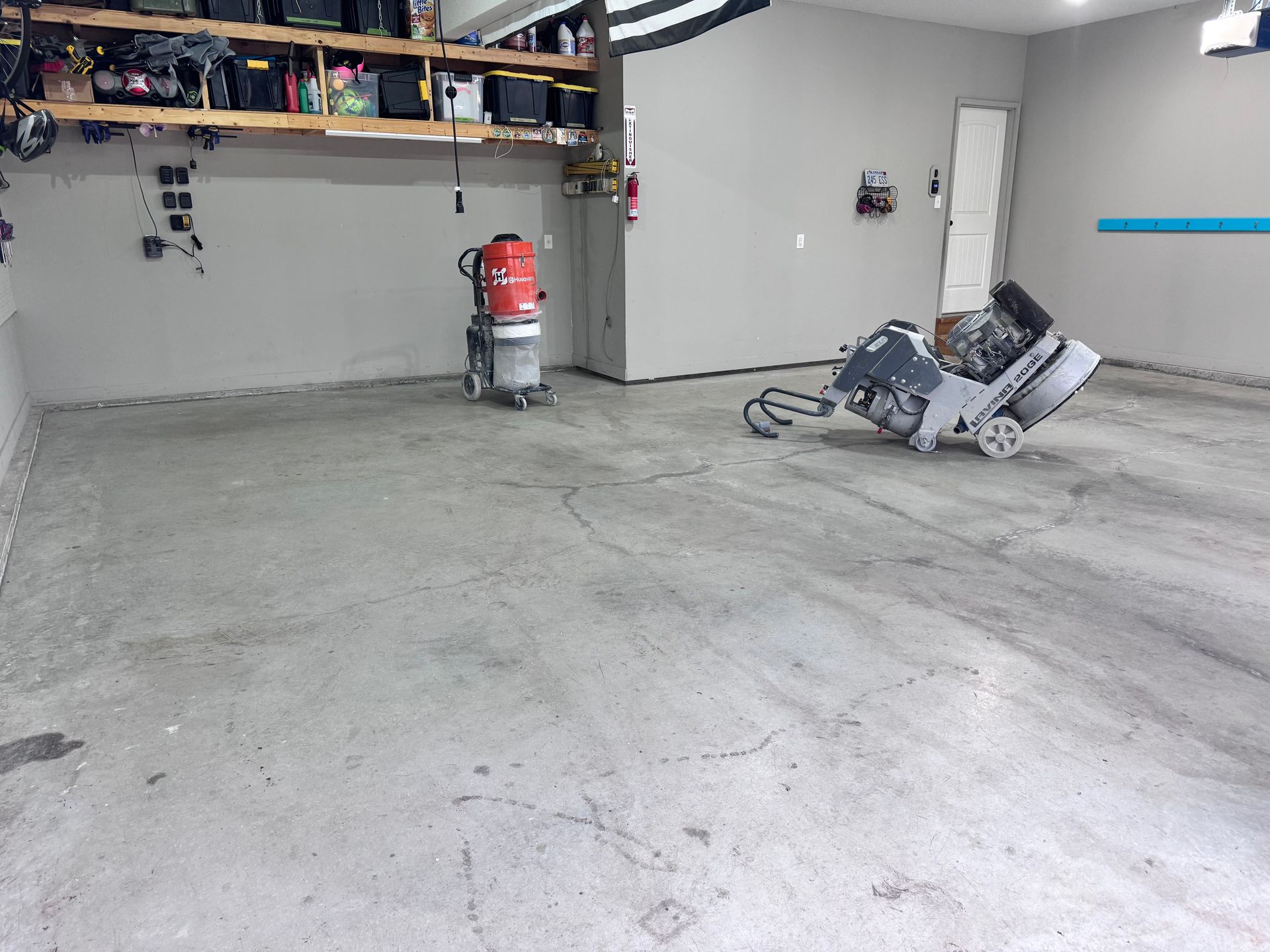 Concrete floor being prepped with grinding machines in a garage.