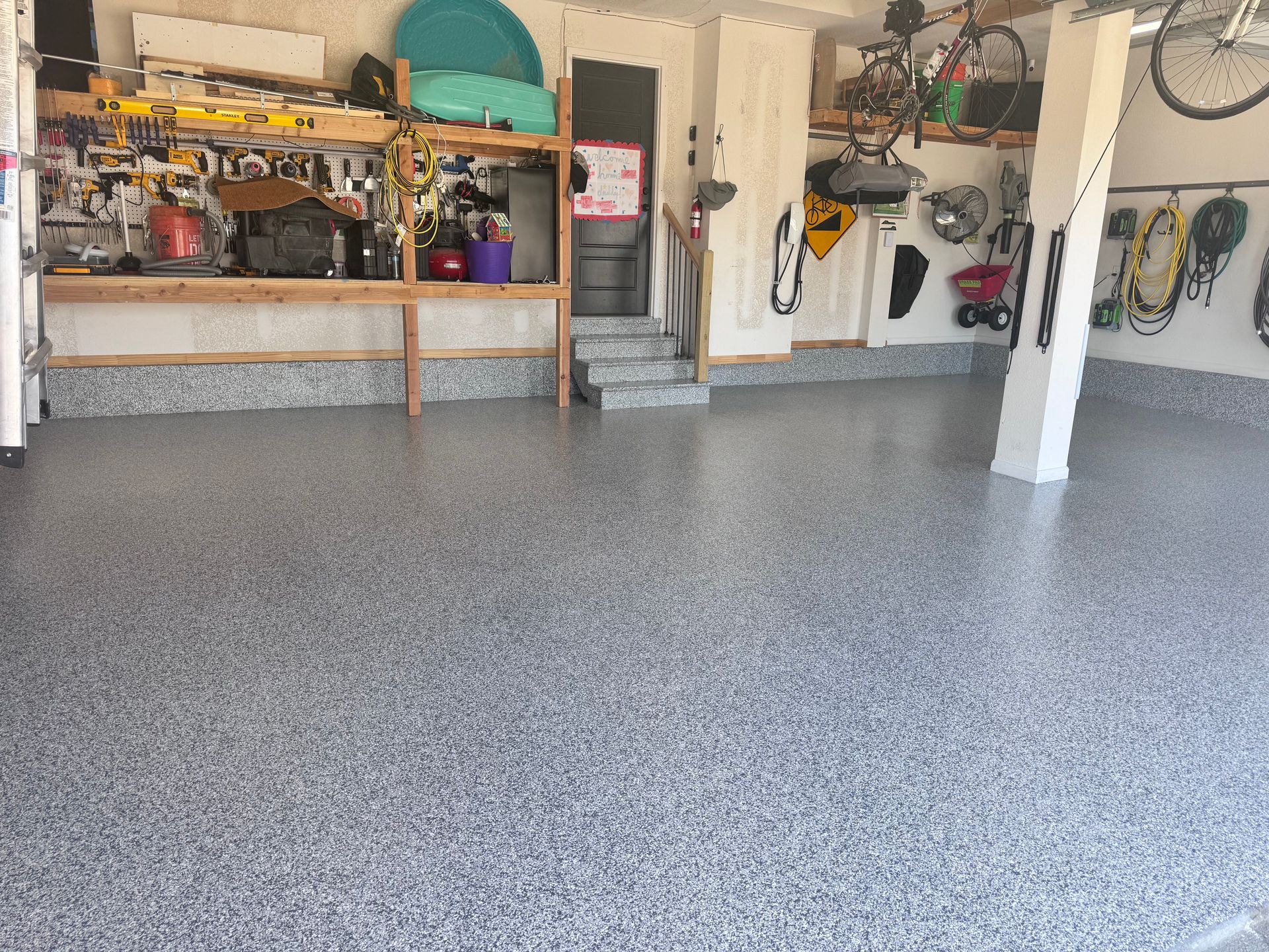 Garage with gray epoxy floor, storage shelves, and bikes on the wall.