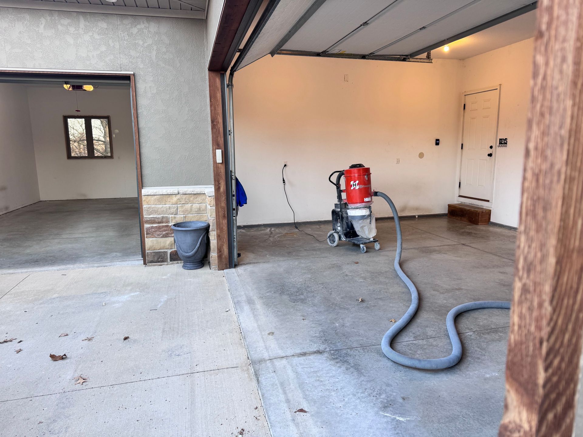 Garage interior with a floor grinding machine, open garage door, and a second empty garage bay.