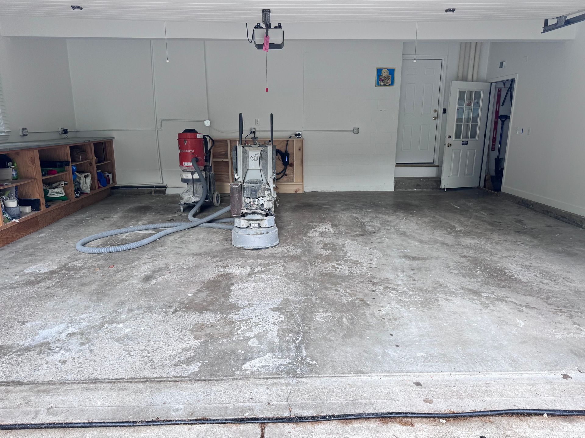 Garage with a concrete floor, a grinding machine, and work tools.