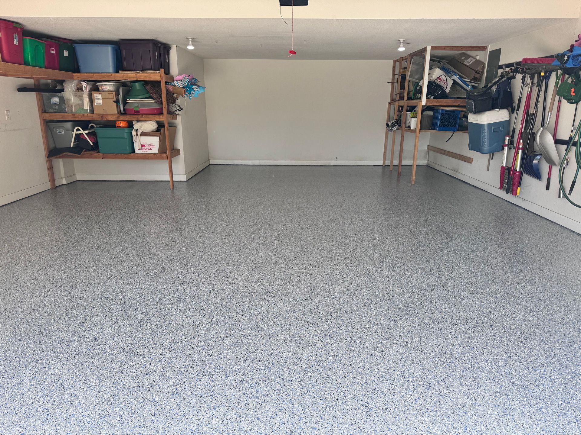 Garage with speckled gray floor, white walls, and storage shelves.