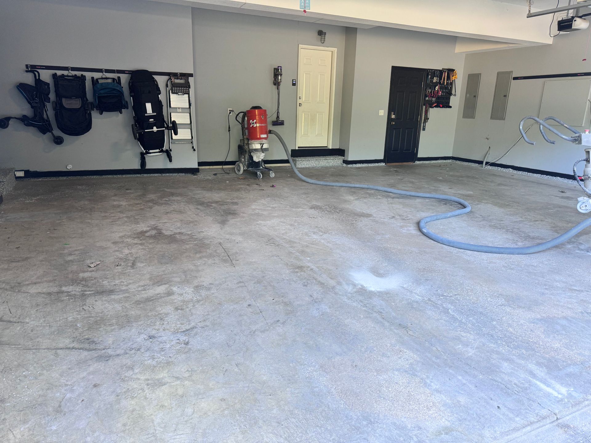Garage interior with concrete floor, walls, and sandblasting equipment; walls are gray and white.