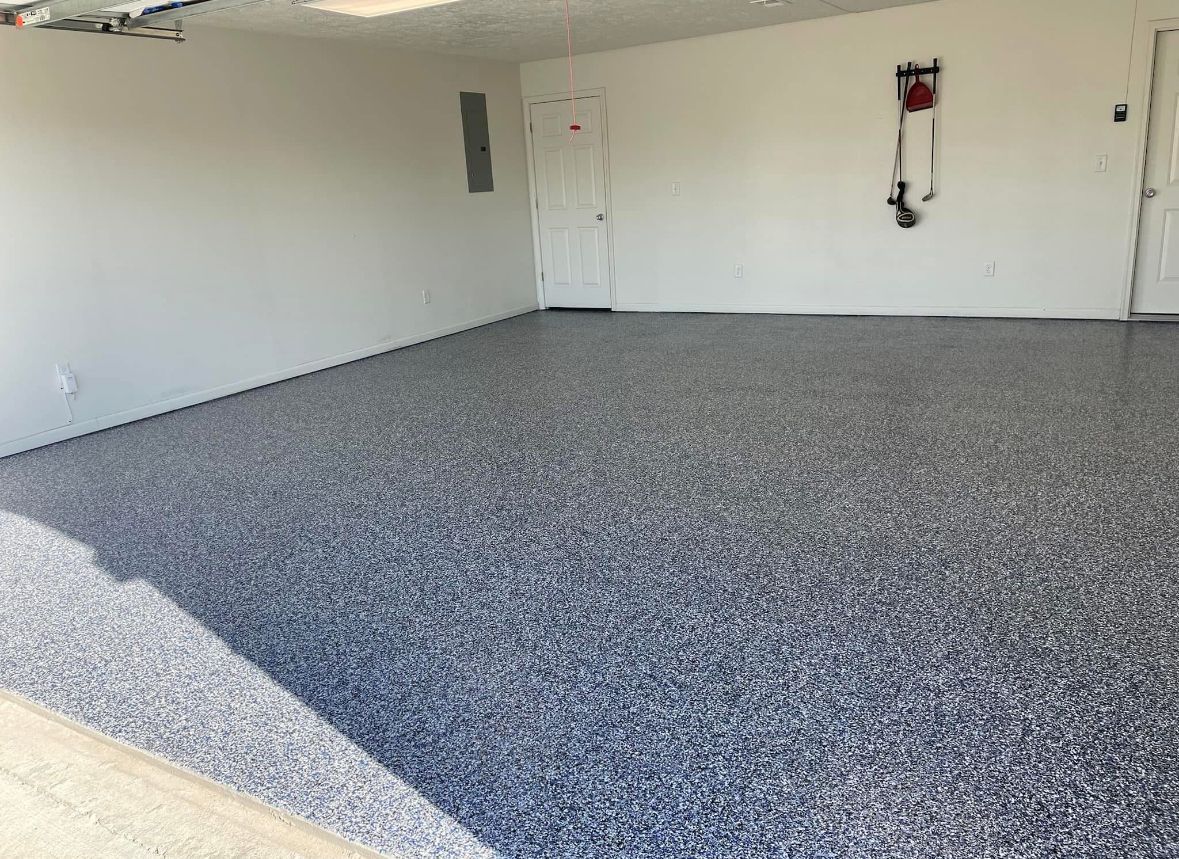 Garage with blue and gray speckled epoxy floor, white walls, and a door.