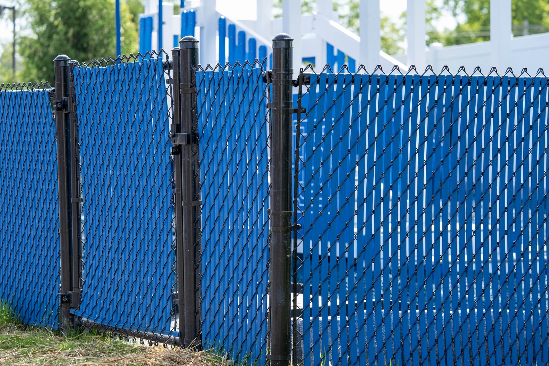 Blue privacy slats woven through a black chain-link fence, outdoors.